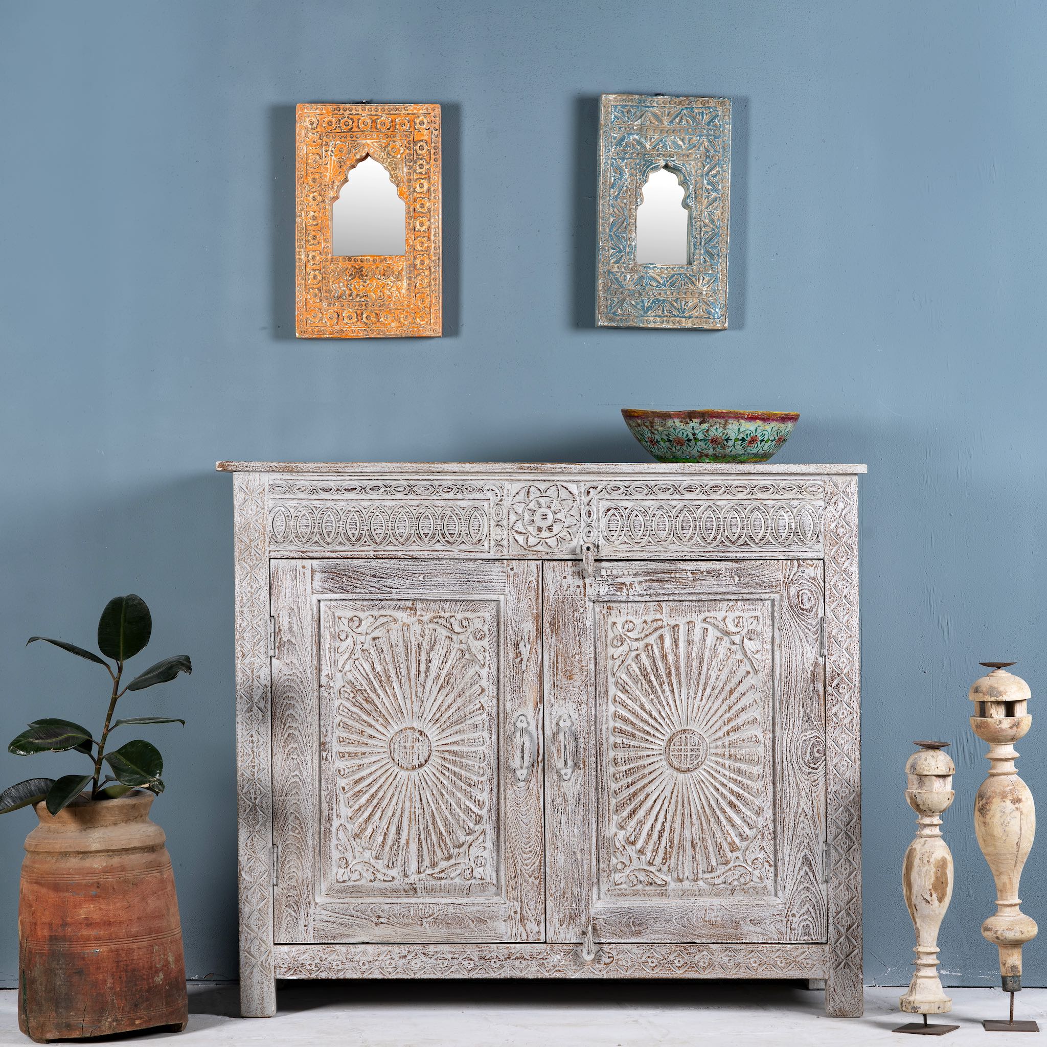 Grey-washed reclaimed wood cabinet with hand-carved floral and sunburst detailing, a vintage furniture piece perfect for rustic or bohemian interiors.