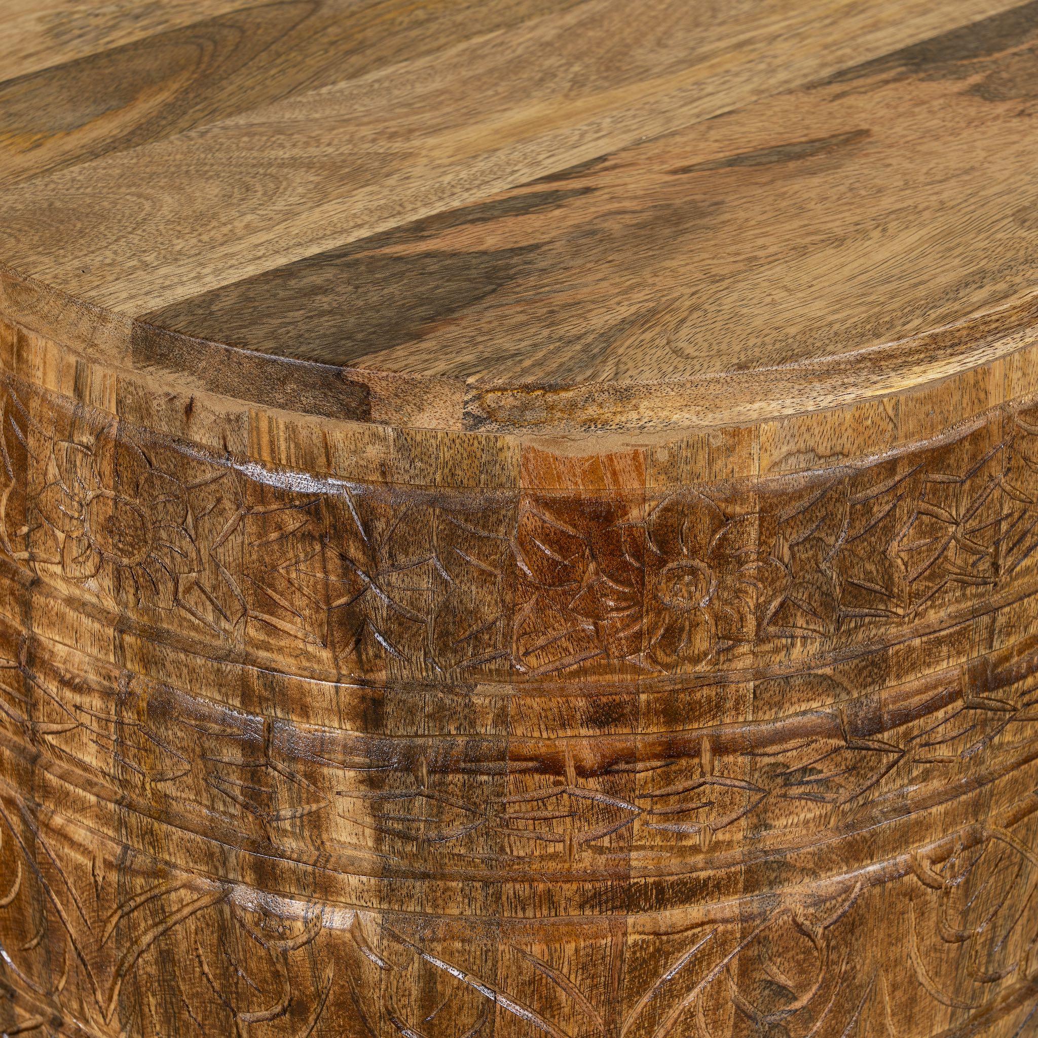 Close up image of a hand-carved mango wood coffee table with barrel shape and warm rustic finish; vintage style coffee table, 45 cm diameter, 55 cm height.