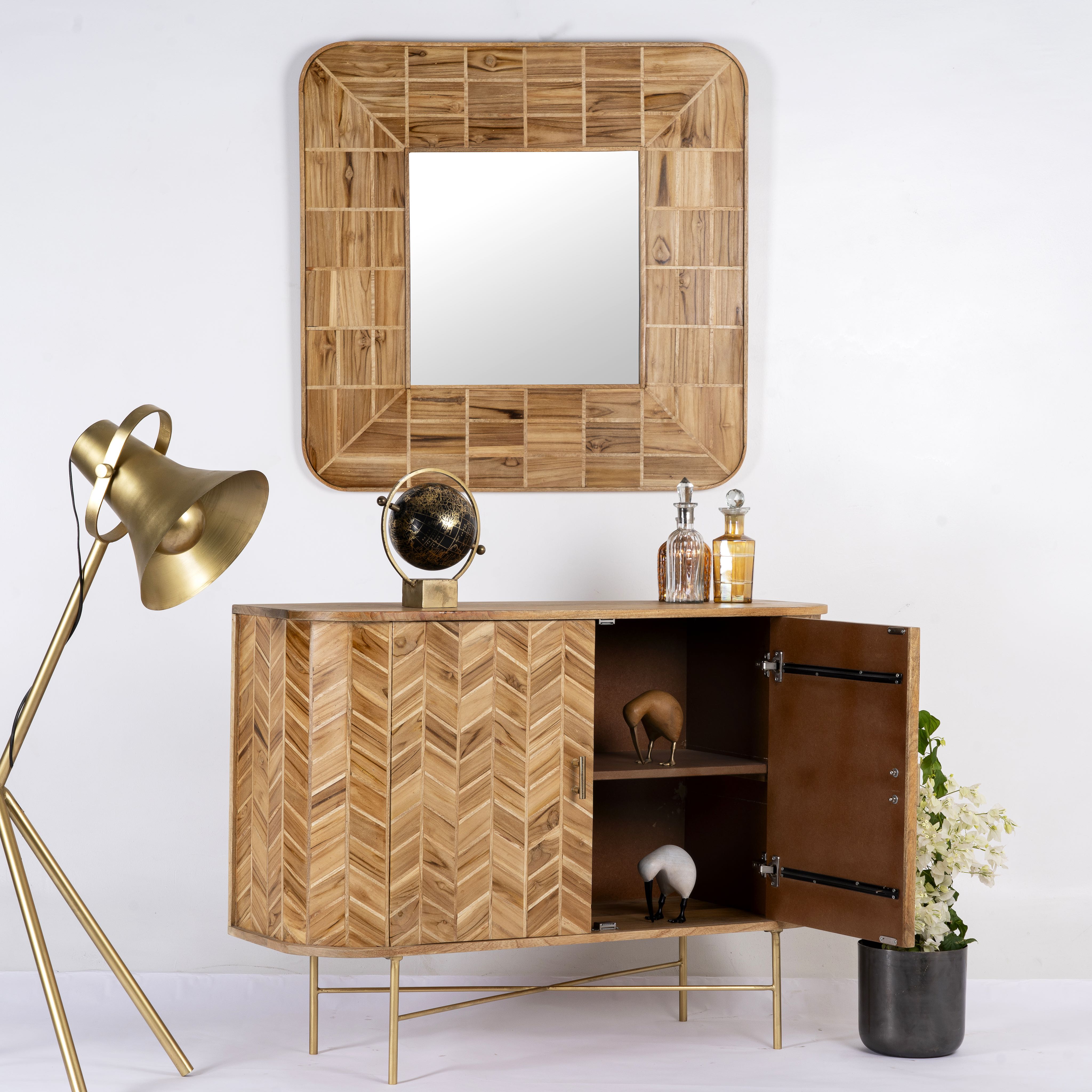Side angle image with open door of a handmade teak wood cabinet with chevron pattern, brass stand, and handles—minimalistic style living room furniture with modern and natural appeal.