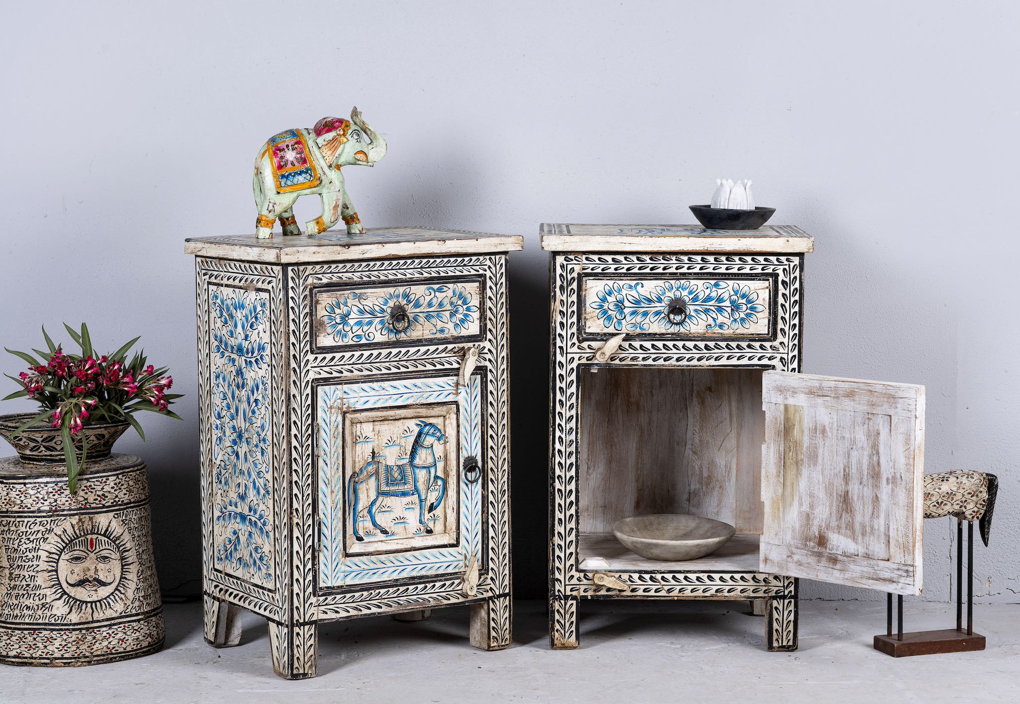 Side angle image with open door o a pair of hand-painted reclaimed wood nightstands with intricate floral and horse motifs in blue and black, crafted in traditional Indian style