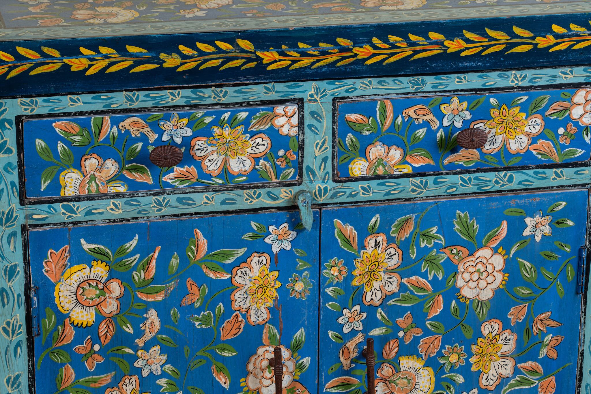 Close up image of a hand-painted cupboard made of reclaimed wood with vibrant floral design – Tvesa model by Om Home & Garden