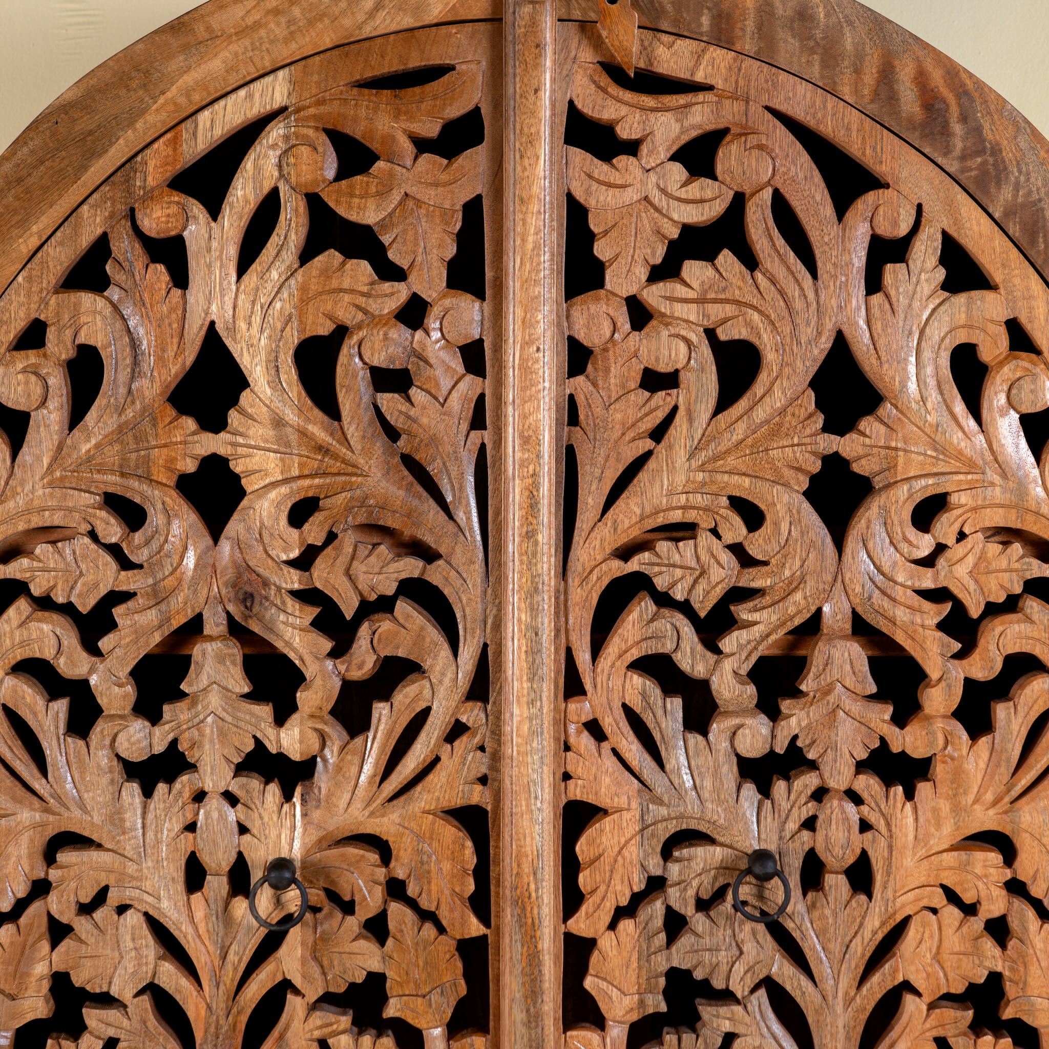 Close up image of a hand carved wooden wardrobe with arc-shaped cabinet design in solid mango wood – Aranya model by Om Home & Garden