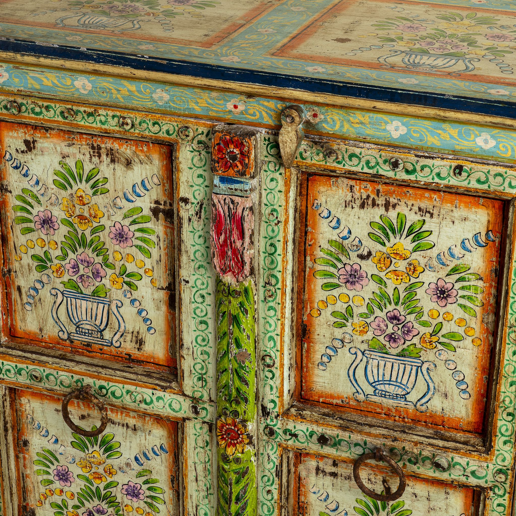 Close up image of a reclaimed wood sideboard with hand painted floral motifs and distressed finish; artisanal storage furniture for bohemian interiors, 170 × 40 × 104 cm.