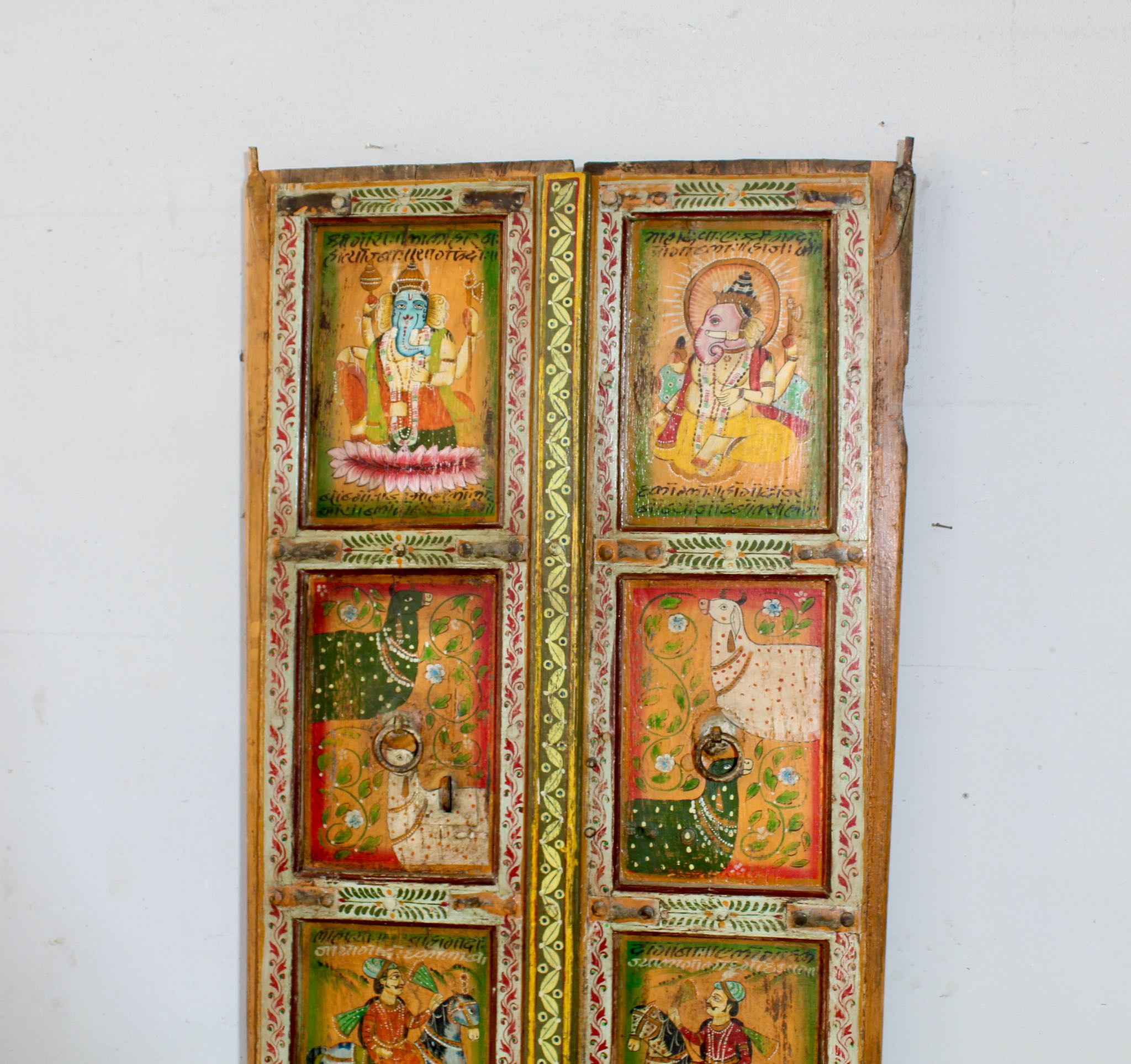Close up image of a hand-painted Indian antique teak door with Hindu gods, elephants, and folk art, reclaimed wood vintage wall panels for vintage home decor.