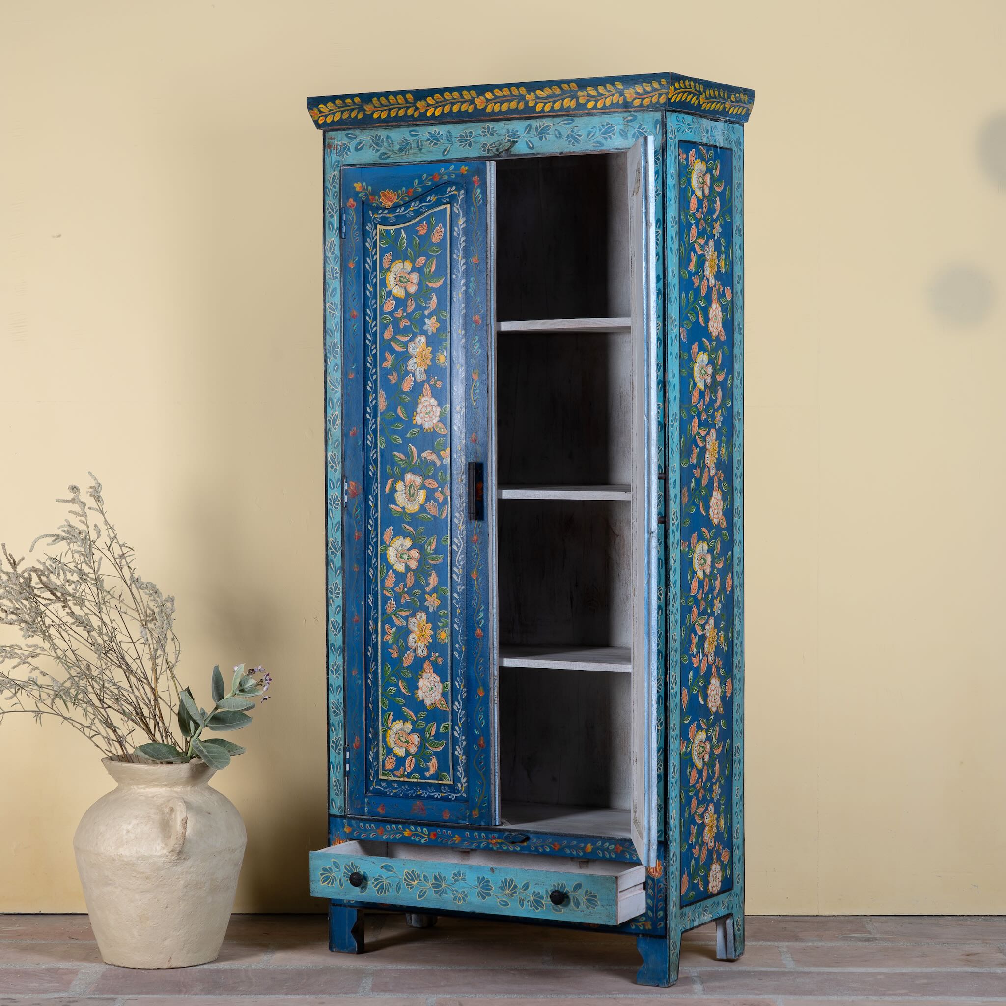 Side angle image of a hand-painted wardrobe made of reclaimed wood in vibrant blue floral design – Yuvika model by Om Home & Garden