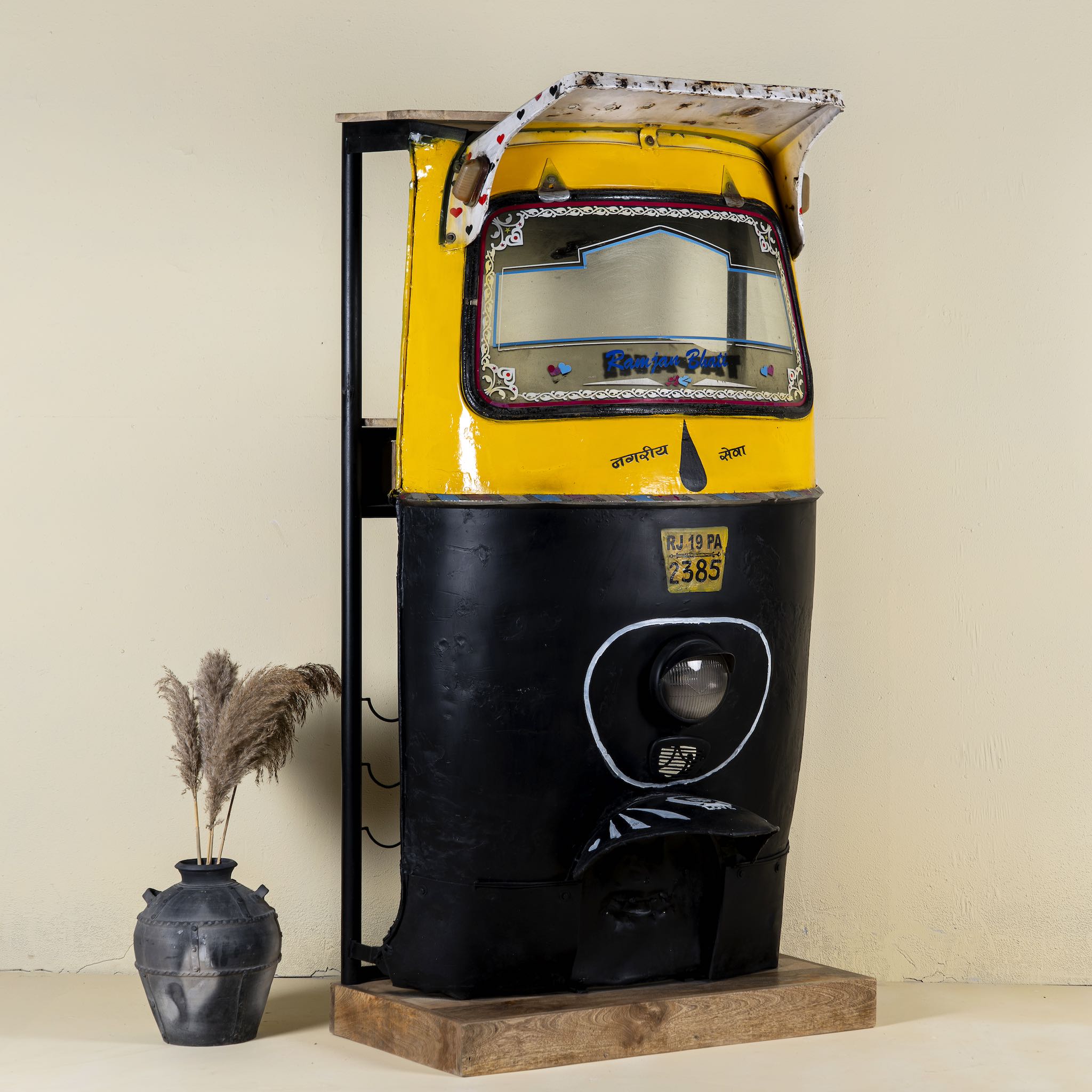 Unique bar table crafted from the front part of an old Indian rickshaw, featuring vibrant yellow and black paint with original details and functioning light.