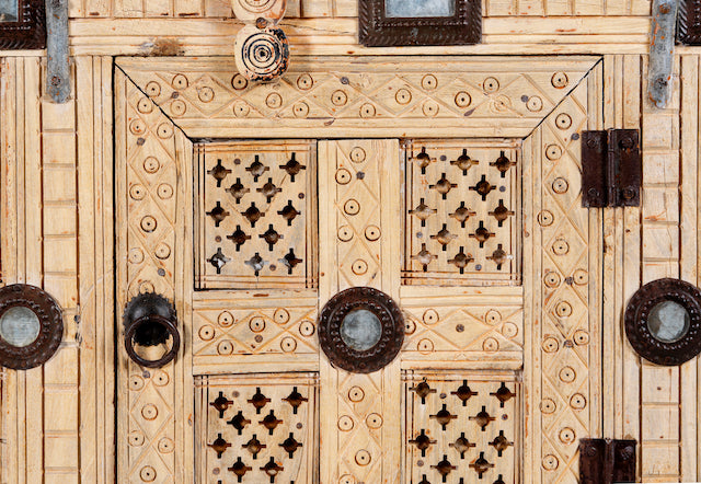 Close up image of an antique Indian treasure chest in solid teak with hand-carved detailing and sandblasted finish. A vintage home accessory ideal for Indian decor, 122 × 96 × 40 cm.