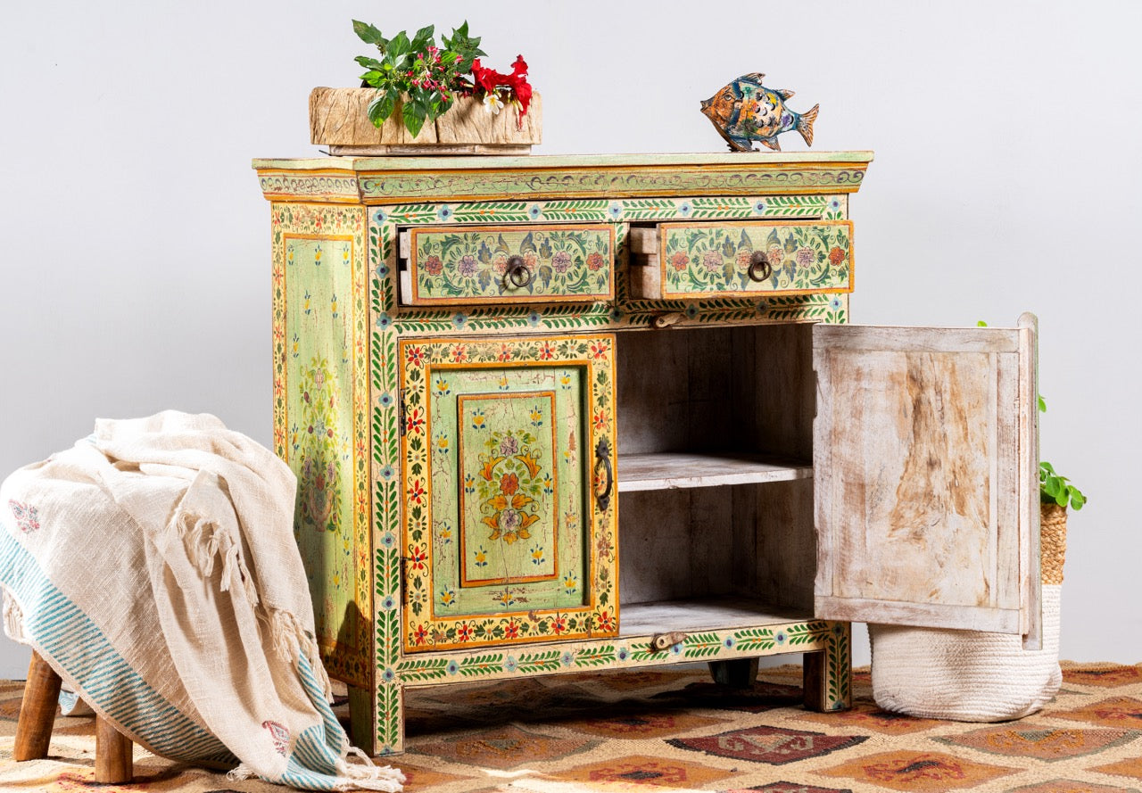 Side angle image of a hand painted green Indian cabinet made from recycled wood with floral motifs, 2 drawers and 2 compartments, 90 × 90 × 40 cm.