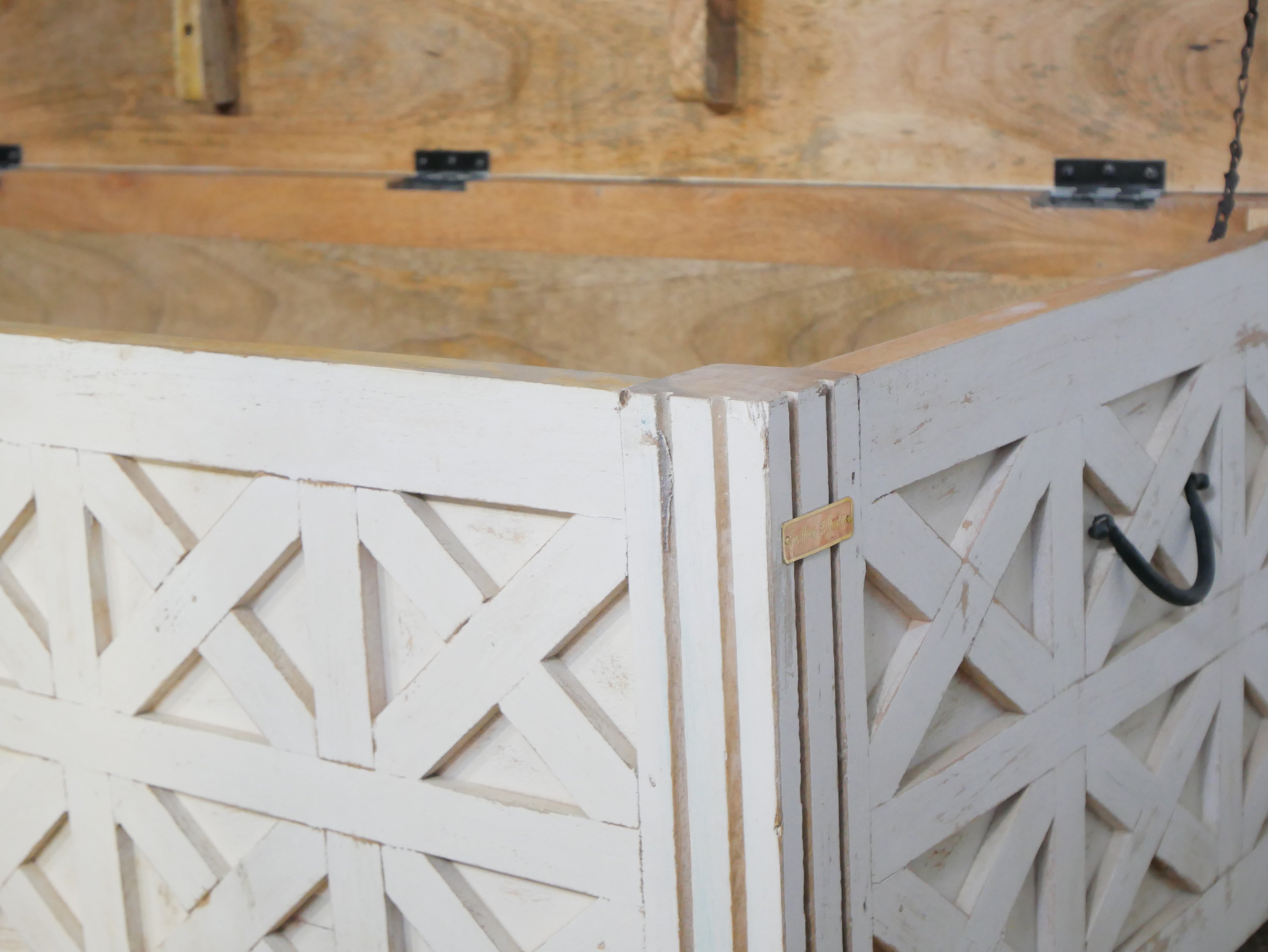 Close up image of a hand-carved mango wood vintage chest front view – styled in Mediterranean living room with books, candles, natural textures, and soft daylight.
