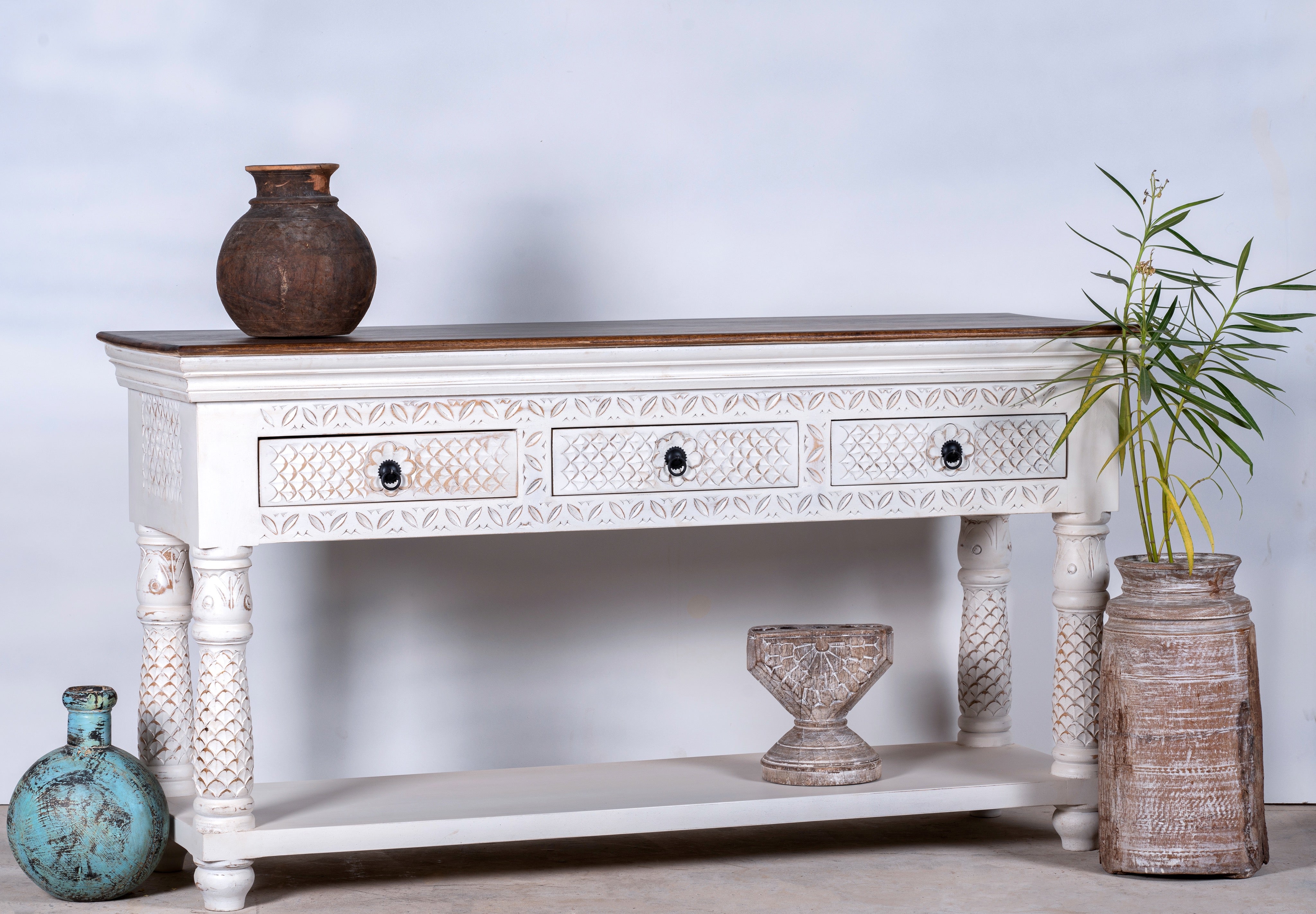 Side angle image of a carved mango wood console table with floral ornamentation; rich, exotic mango wood furniture, 150 × 90 × 45 cm.