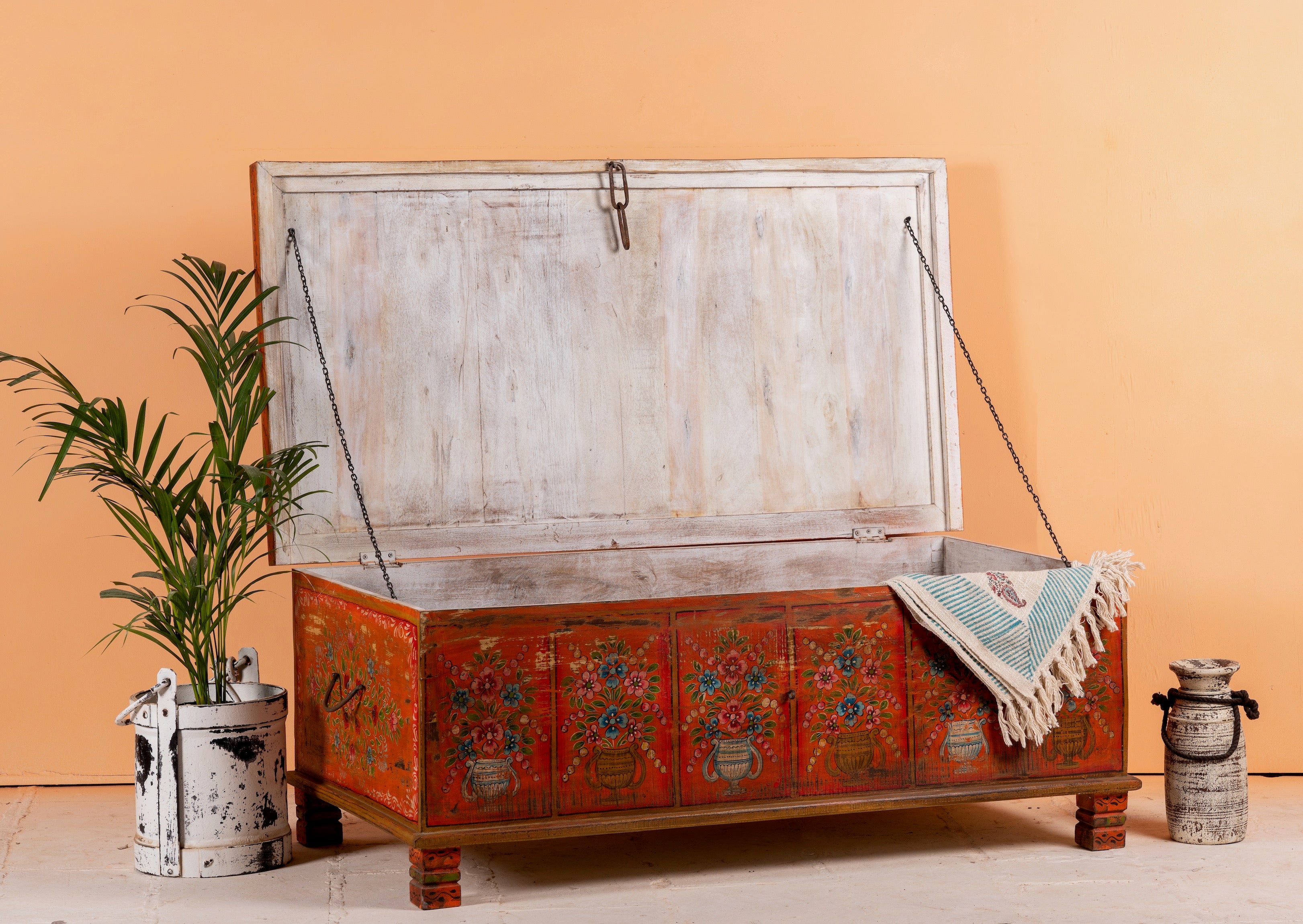 Side angle image with open lid of a hand-painted teak reclaimed wood chest – sustainable handcrafted furniture serving as a coffee table and artistic storage solution.
