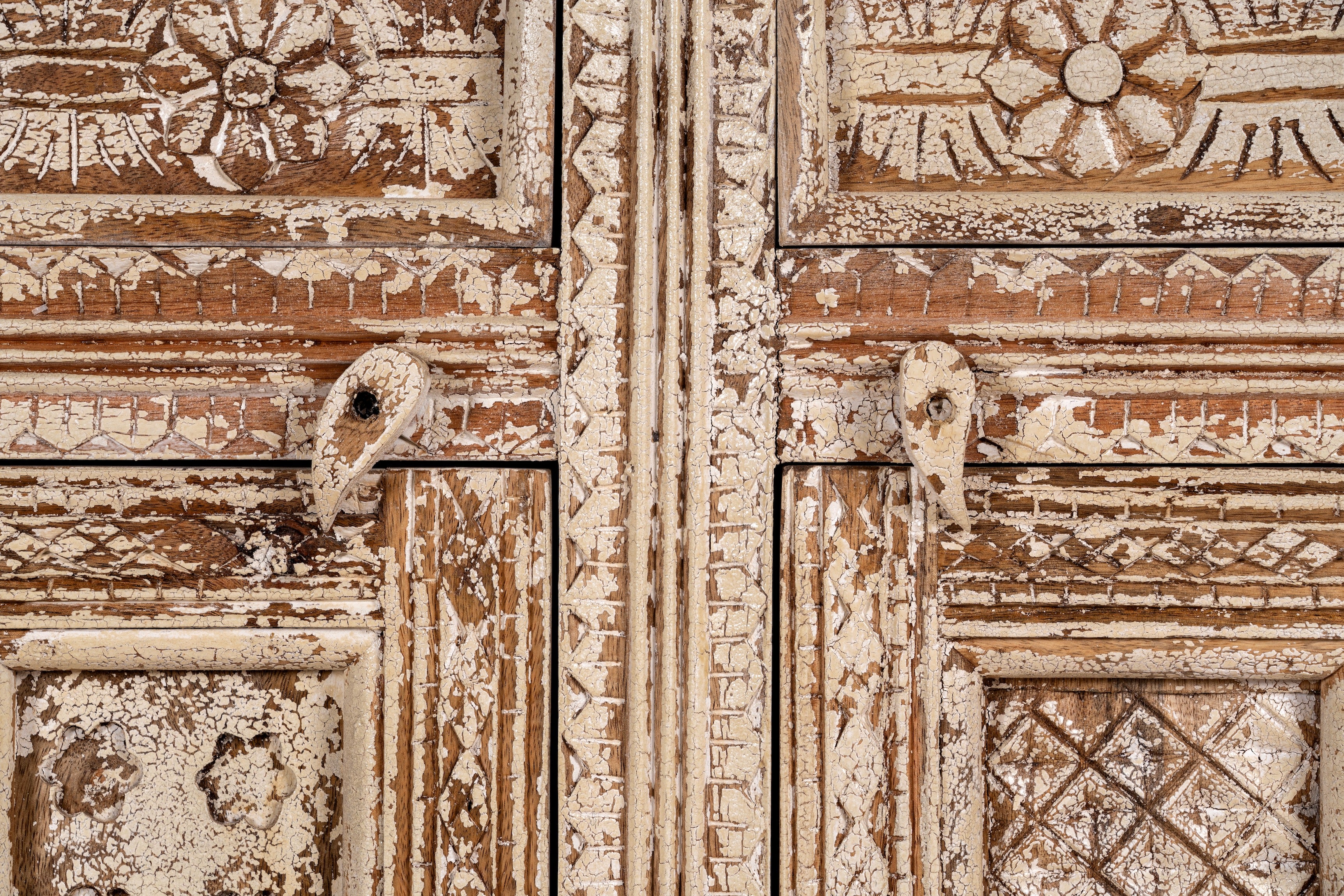 Close up image of a hand-carved mango wood cabinet with three drawers and vintage distressed finish; ideal for mango wood furniture lovers and vintage home decor, 150 × 110 × 40 cm.