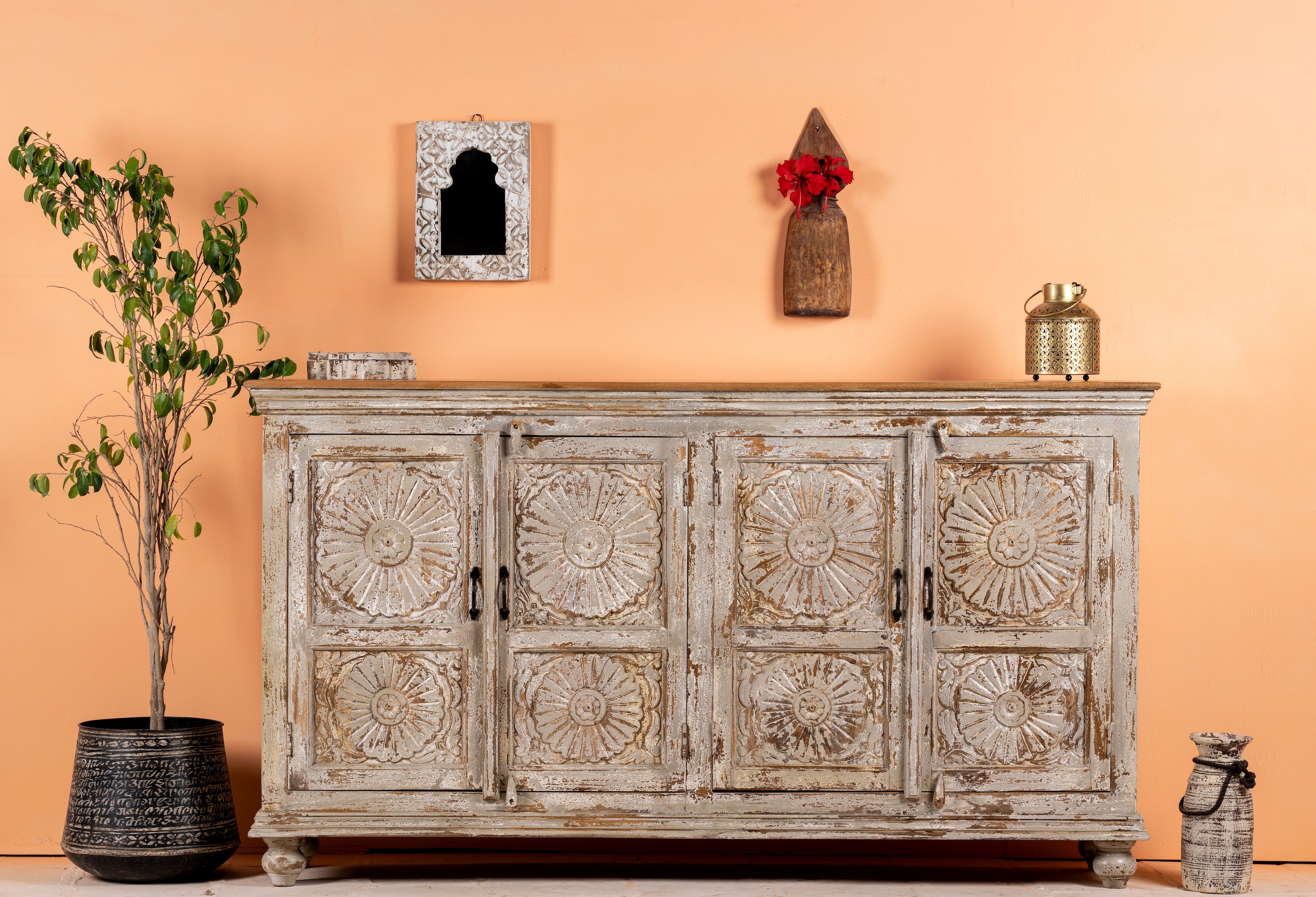 Lifestyle image of a handcrafted carved sideboard made from reclaimed wood with floral motifs and distressed finish; suitable as bedroom furniture, 180 × 40 × 100 cm.