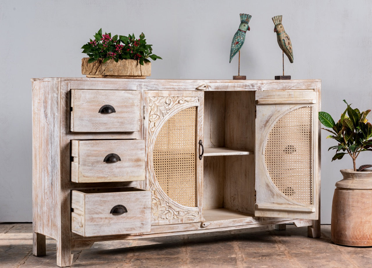 Side angle image with open doors of a white mango wood and rattan sideboard with six drawers and two compartments—handcrafted bedroom furniture blending Indian artistry with Scandinavian design.