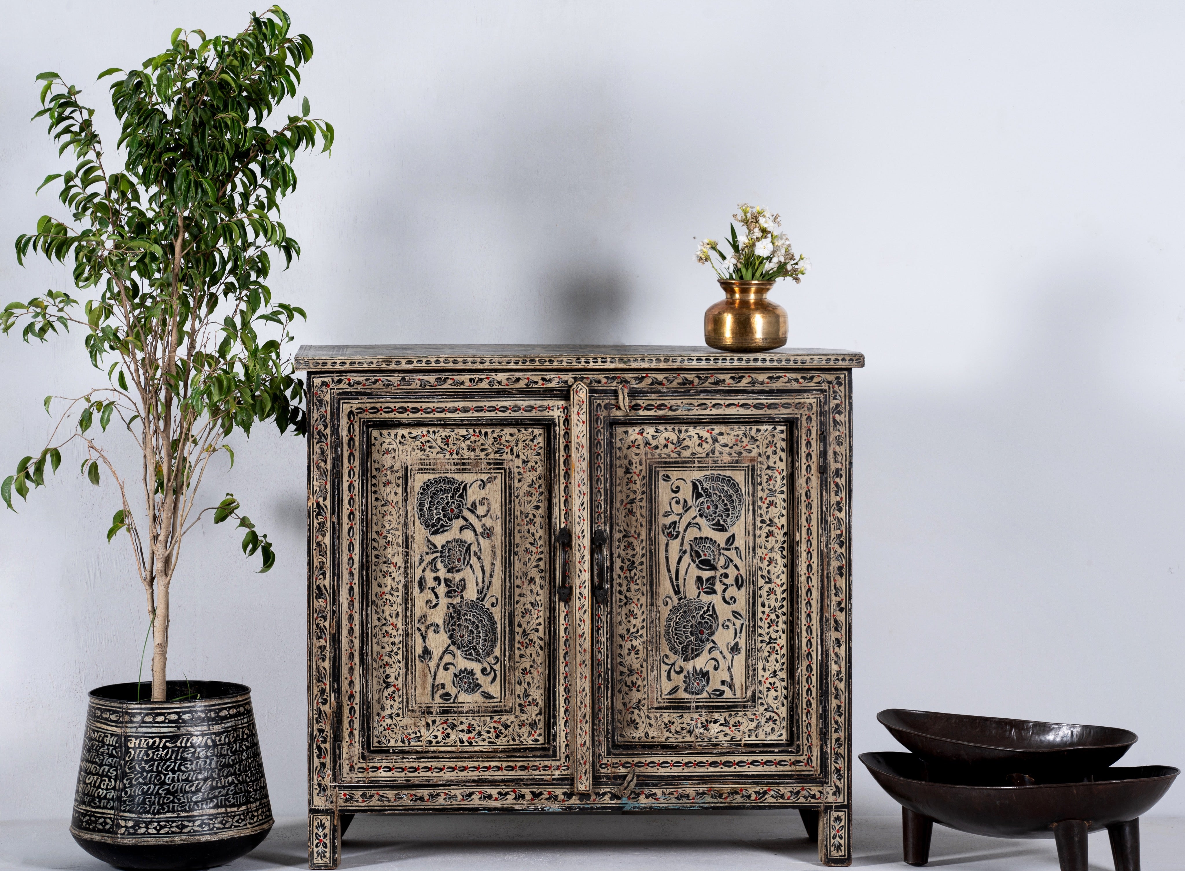 Lifestyle image of a hand-painted cupboard made from reclaimed wood with Indian floral motifs; ideal for boho chic living room or unique furniture decor, 100 × 92 × 36 cm.