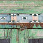 Close up image of a reclaimed teak wood vitrine with distressed green finish, ceramic inlays, and glass-panelled doors – sustainable furniture with vintage Indian charm.