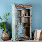 Side angle image with open door of a reclaimed teak wood display cabinet with light blue shabby chic finish and ceramic inlays – sustainable teak wood showcase with glass doors.