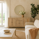 Lifestyle imagination of a sandblasted wooden sideboard with three compartments and two small drawers, Ibiza style living room furniture in light natural finish, 200×40×90 cm.