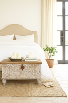 Lifestyle image of a hand-carved mango wood chest box with floral whitewashed detailing and iron handles – vintage home accessory and unique furniture with rustic charm.