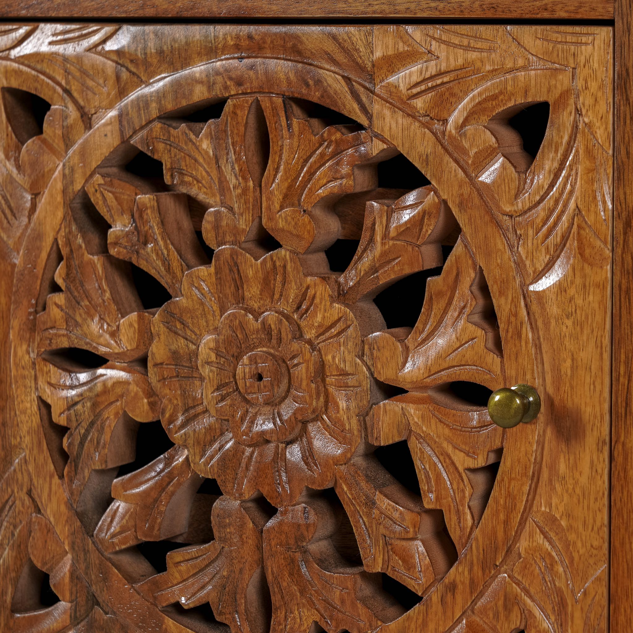 Close up image of a pair of hand-carved bedside tables made of mango wood, featuring intricate round floral hand carvings on the doors. 