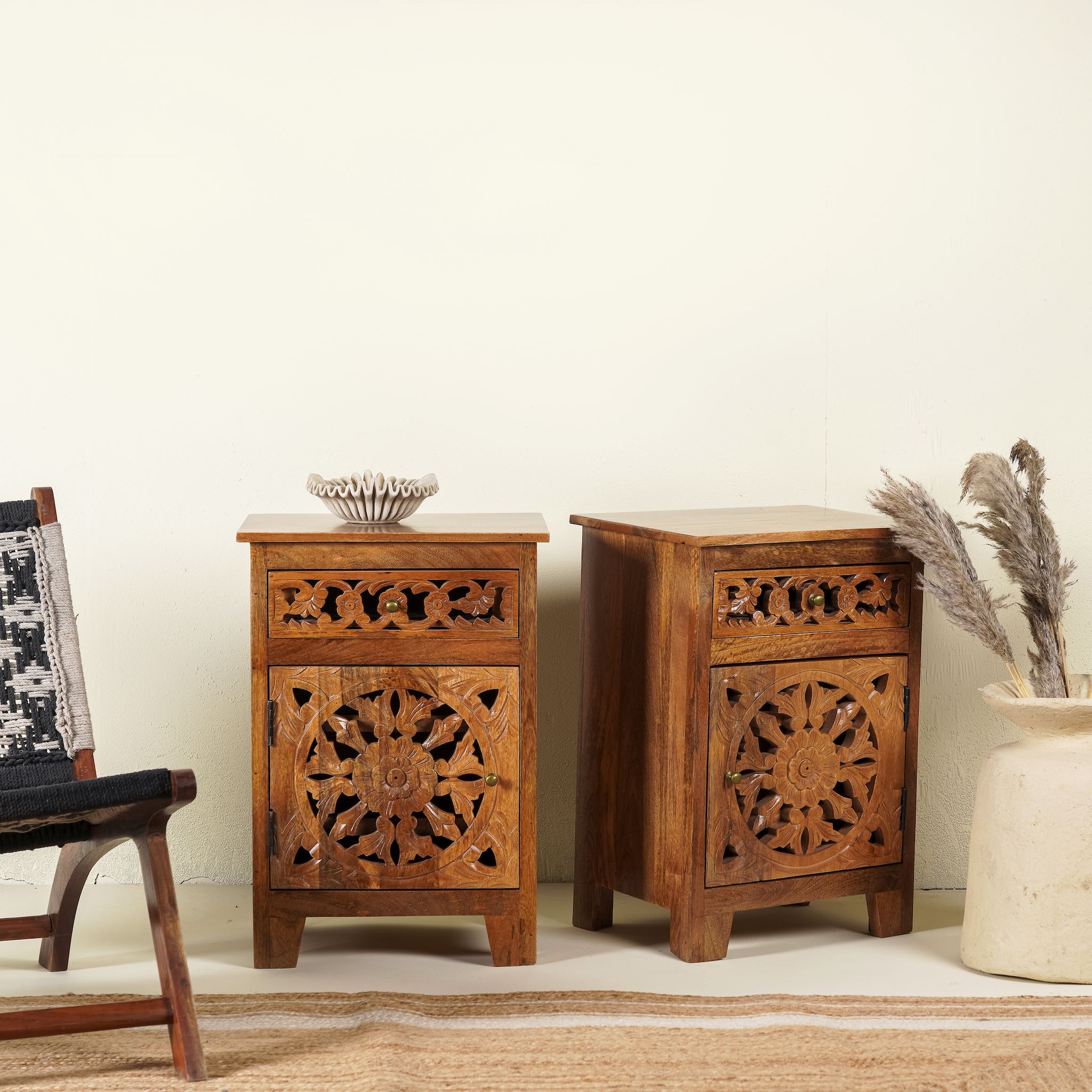 Pair of hand-carved bedside tables made of mango wood, featuring intricate round floral hand carvings on the doors. 