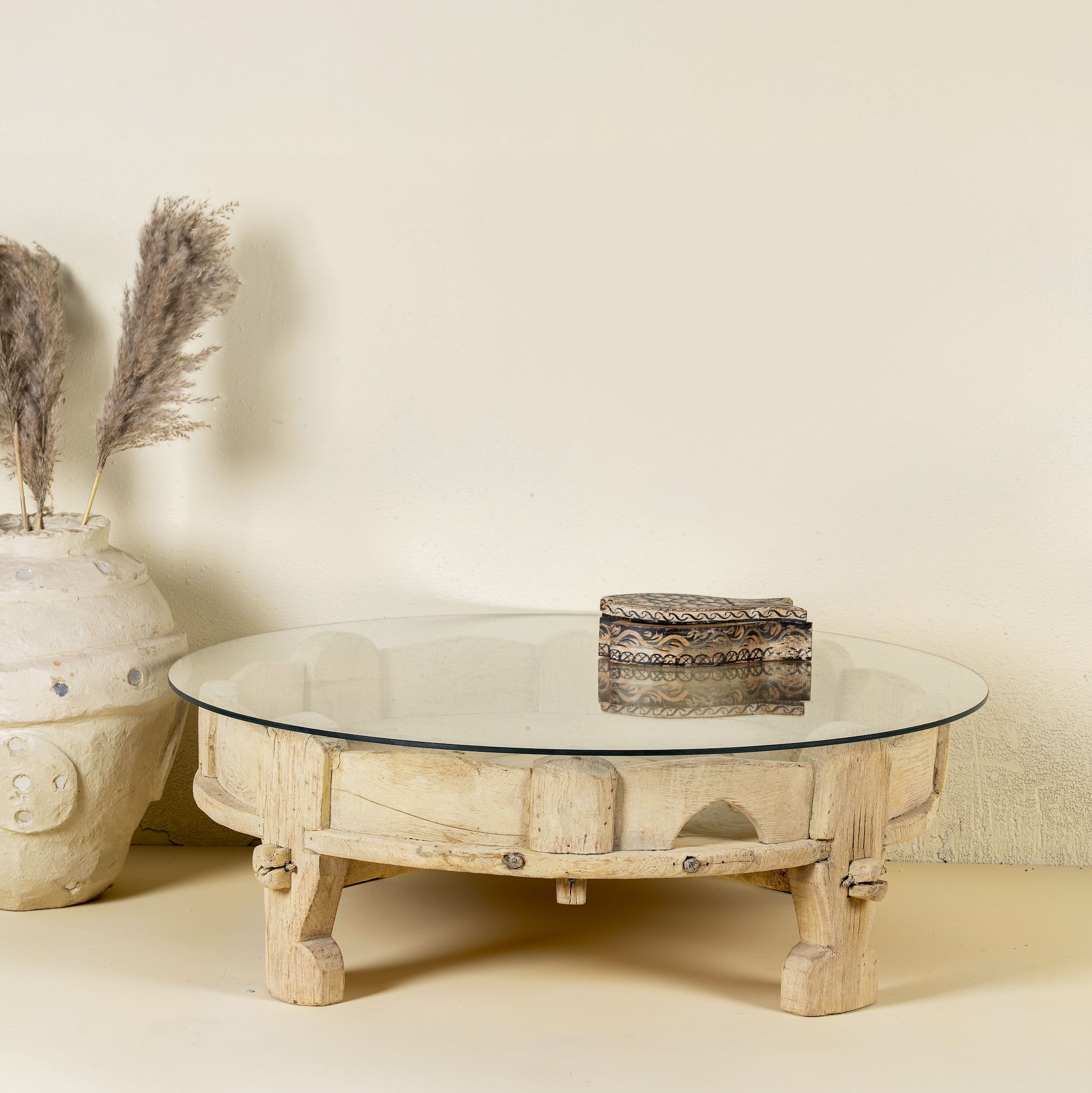 Round reclaimed teak coffee table with glass top and hand-carved base; rustic vintage design, 84 cm diameter, 28 cm height.