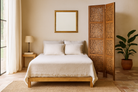 Lifestyle image of a foldable room partition made from mango wood, featuring four panels with intricate hand-carved floral and lattice designs, finished in a warm natural tone and connected by black metal hinges for flexible positioning.
