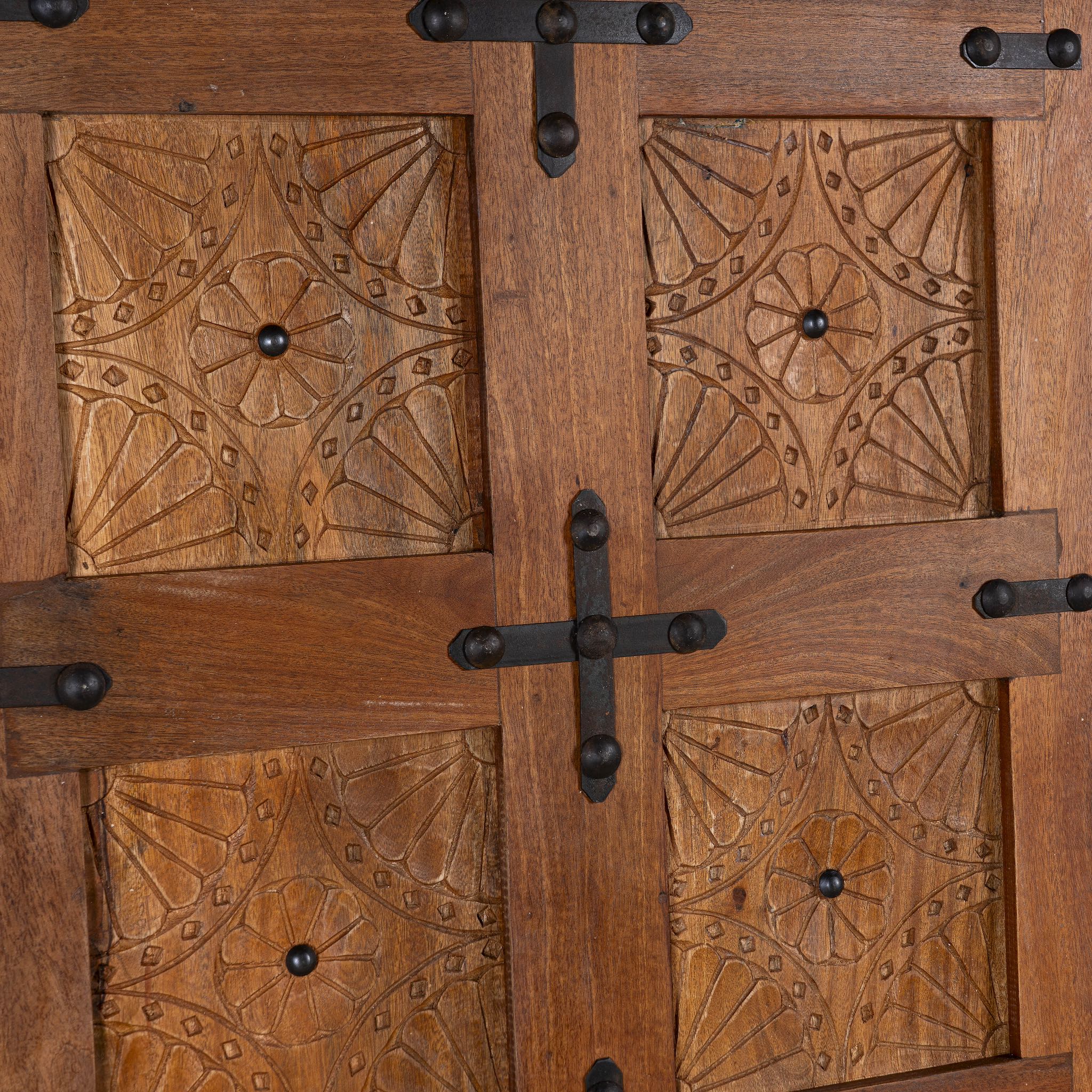 Close up picture of a sliding door panel made from reclaimed wood with detailed hand carvings and traditional iron fittings, combining rustic elegance with functional design.

