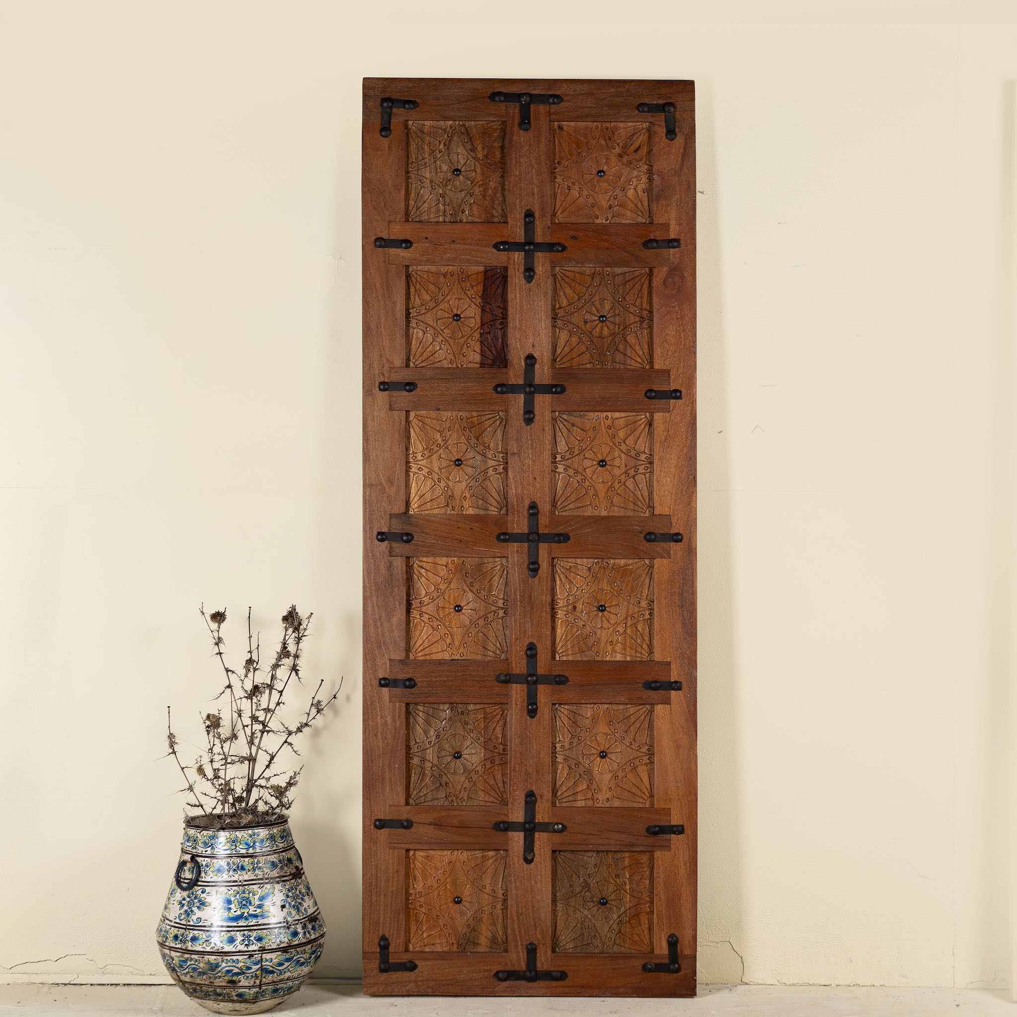 Sliding door panel made from reclaimed wood with detailed hand carvings and traditional iron fittings, combining rustic elegance with functional design.

