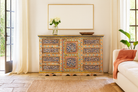 Lifestyle scene of a hand-painted reclaimed wood sideboard with floral motifs – a unique piece of sustainable furniture for vibrant Indian home decor.