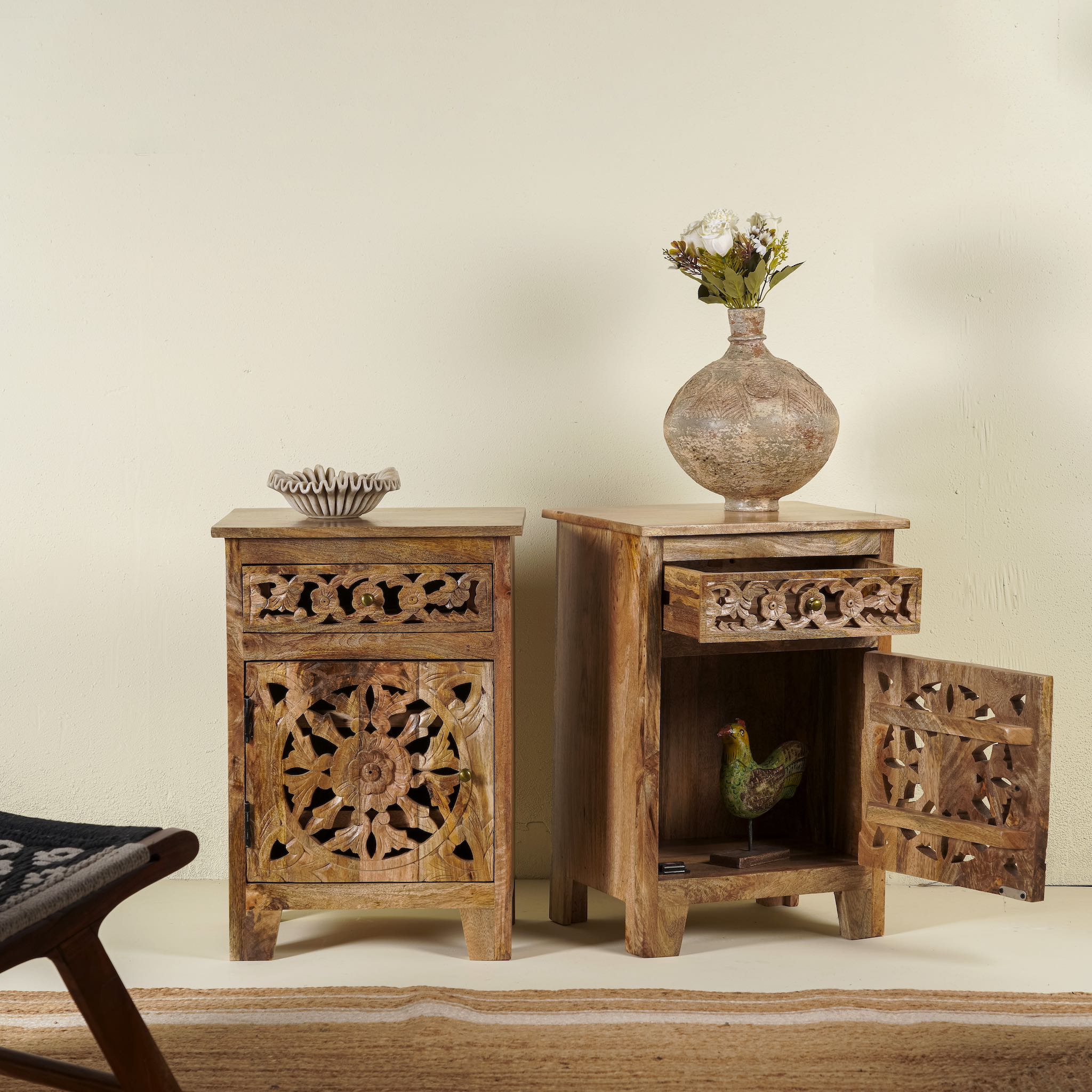 Open door picture of a pair of hand-carved bedside tables made of mango wood, featuring intricate round floral hand carvings on the doors. 