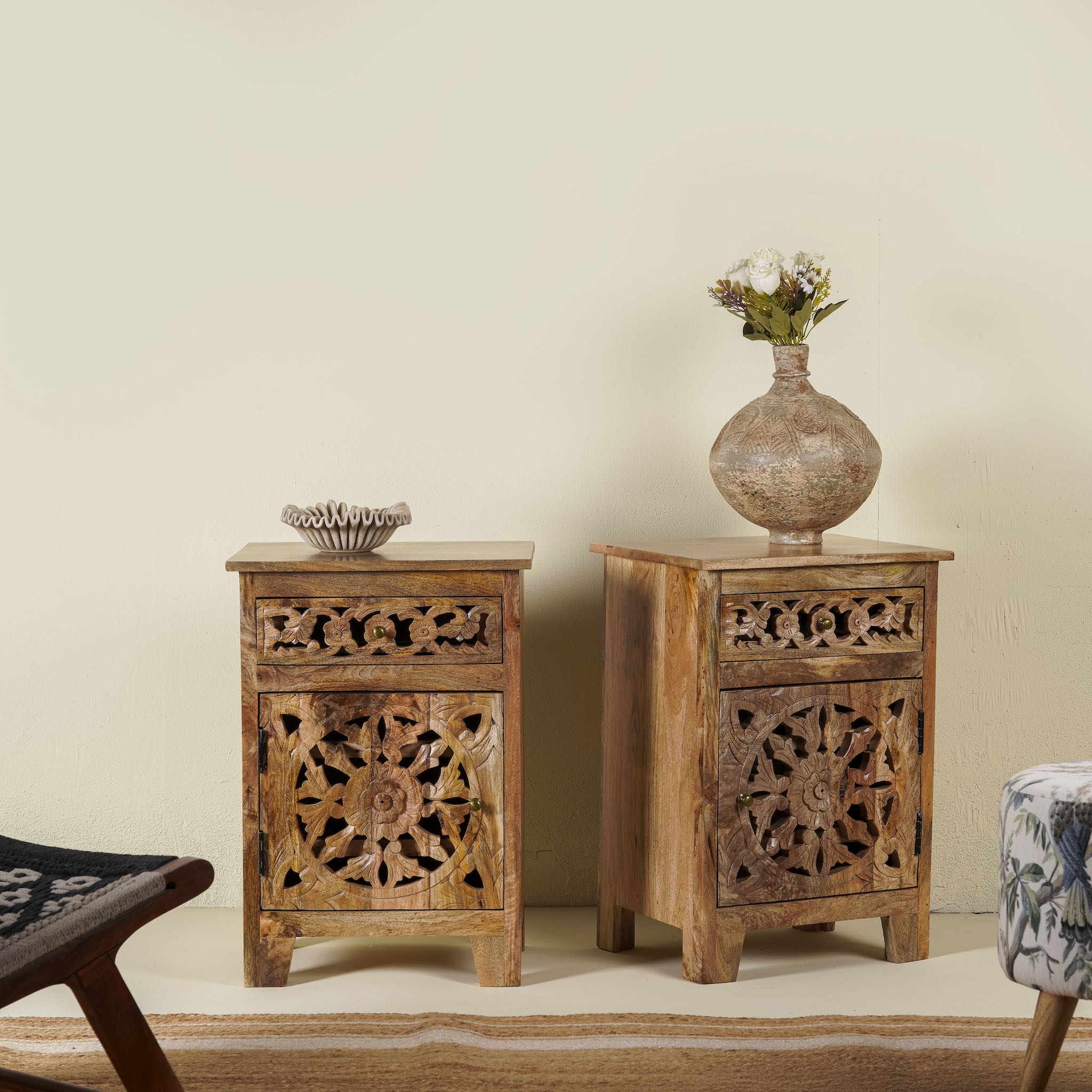 Pair of hand-carved bedside tables made of mango wood, featuring intricate round floral hand carvings on the doors. 