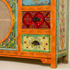 Close up of the leg part of a vintage style furniture sideboard with hand-painted floral motifs and rattan door inserts, bohemian rattan door furniture, 160 × 40 × 90 cm.