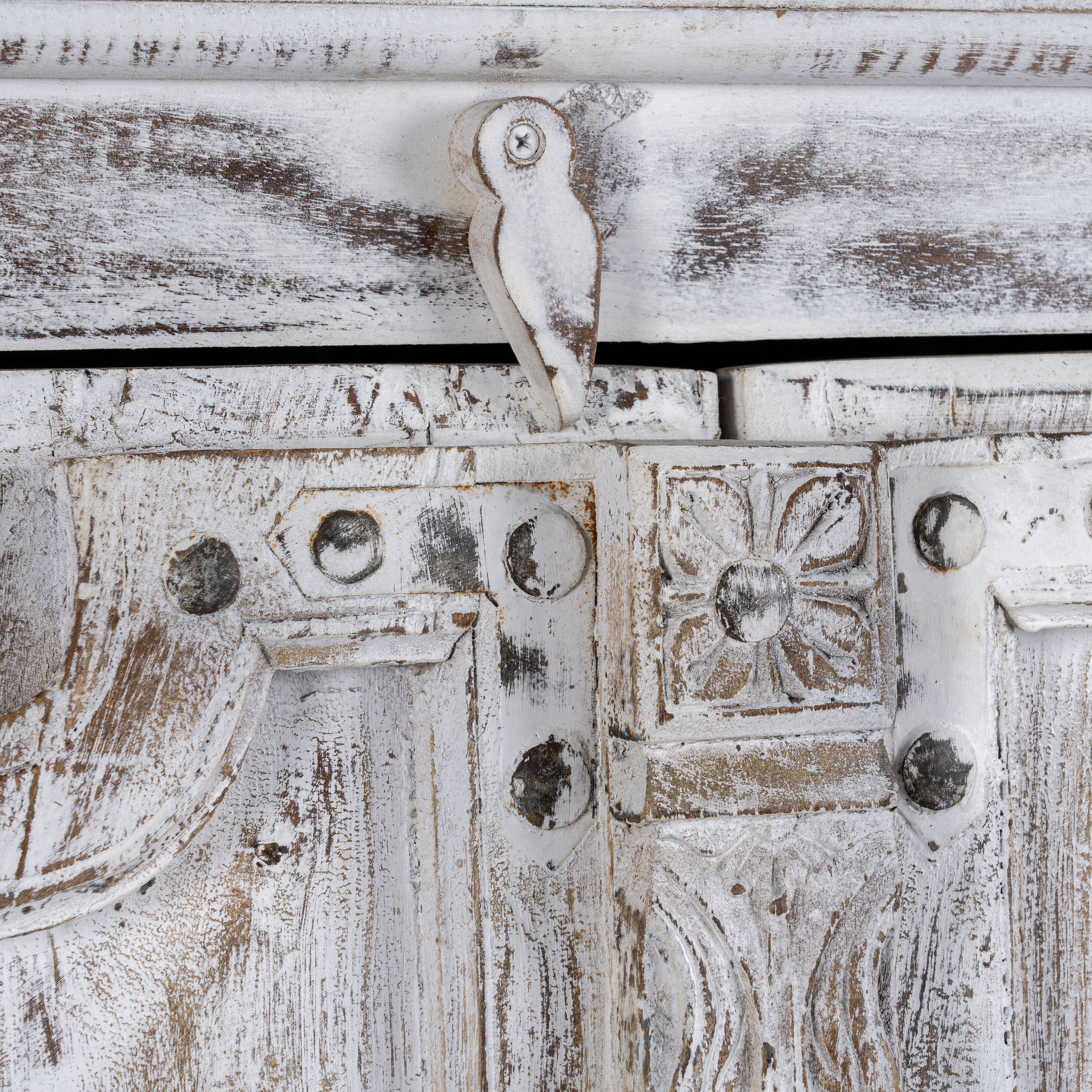 Close up image of a handcrafted cabinet with reclaimed Indian window frame doors, white-washed finish, and iron accents – vintage home decor with teak furniture appeal.