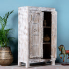 Side angle with open door image of a handcrafted cabinet with reclaimed Indian window frame doors, white-washed finish, and iron accents – vintage home decor with teak furniture appeal.