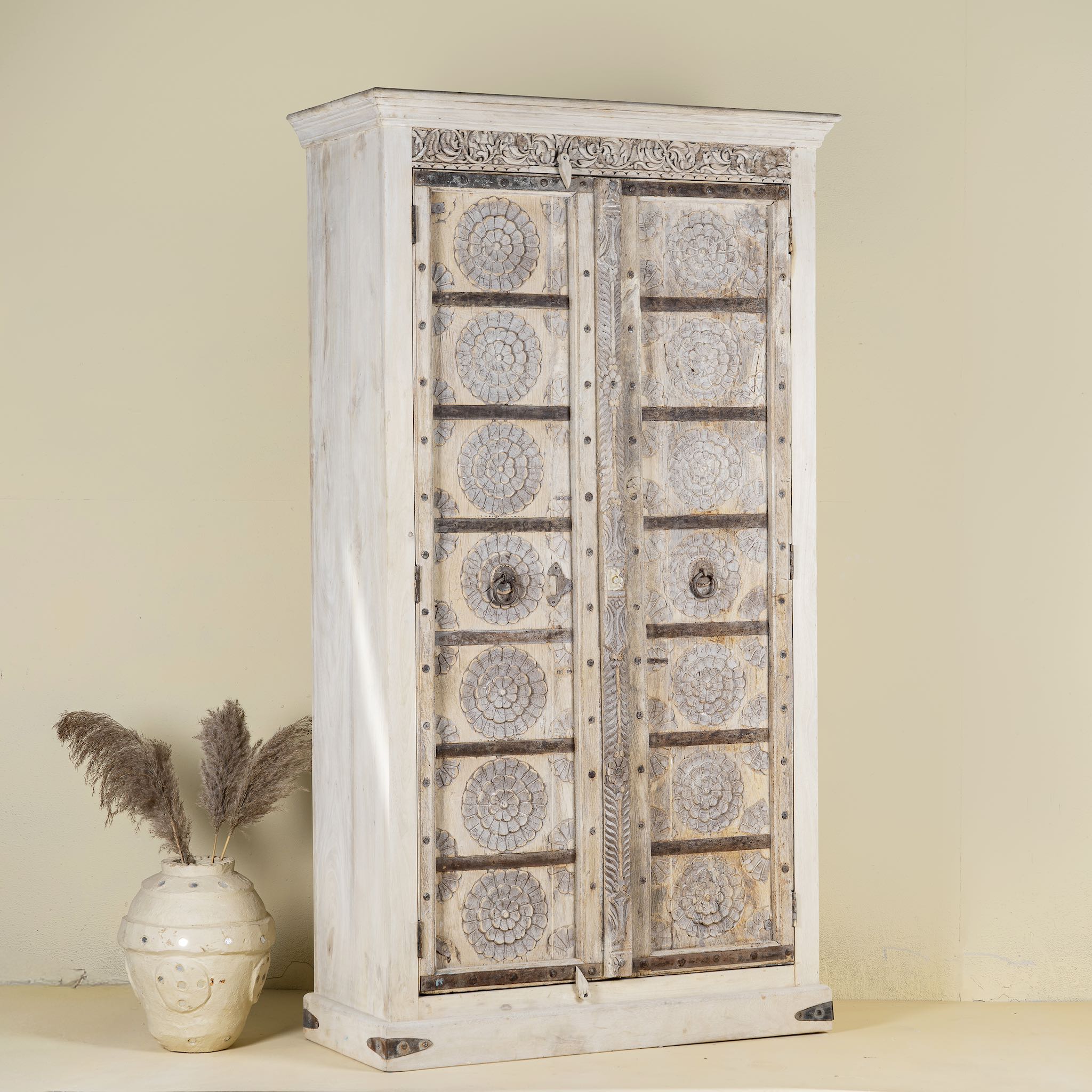 Side view of a old teak door wardrobe with floral carvings and original iron fittings.