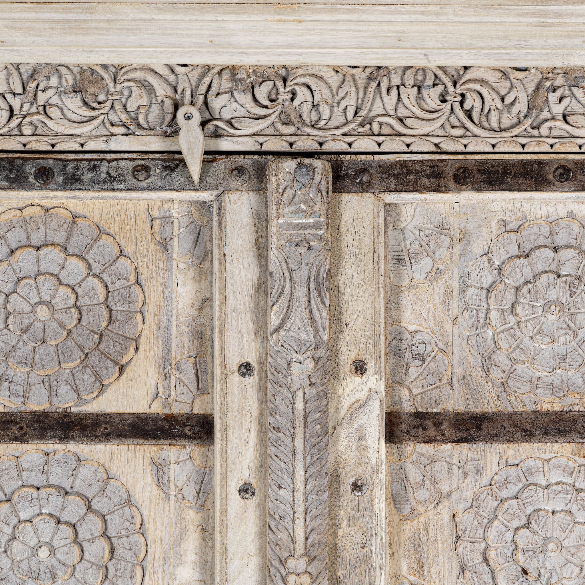 Close up picture of a old teak door wardrobe with floral carvings and original iron fittings.