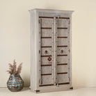 Side angle image of a handcrafted wooden wardrobe made from antique Indian teak doors with iron accents and floral carvings, combined with a solid mango wood body. A tall, rustic cabinet ideal for vintage-inspired or heritage-style interiors.