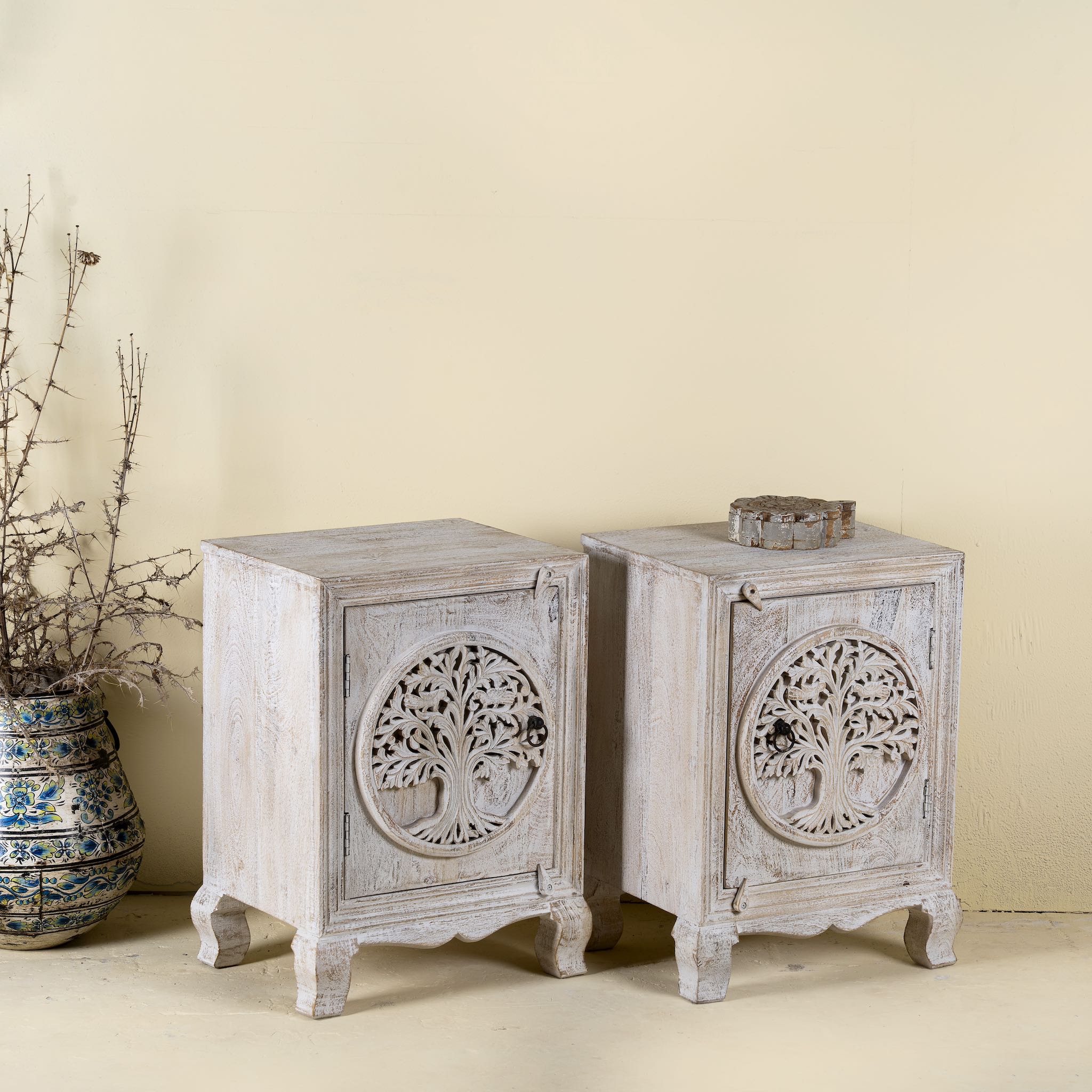 Two wooden side tables with tree carvings on a beige background