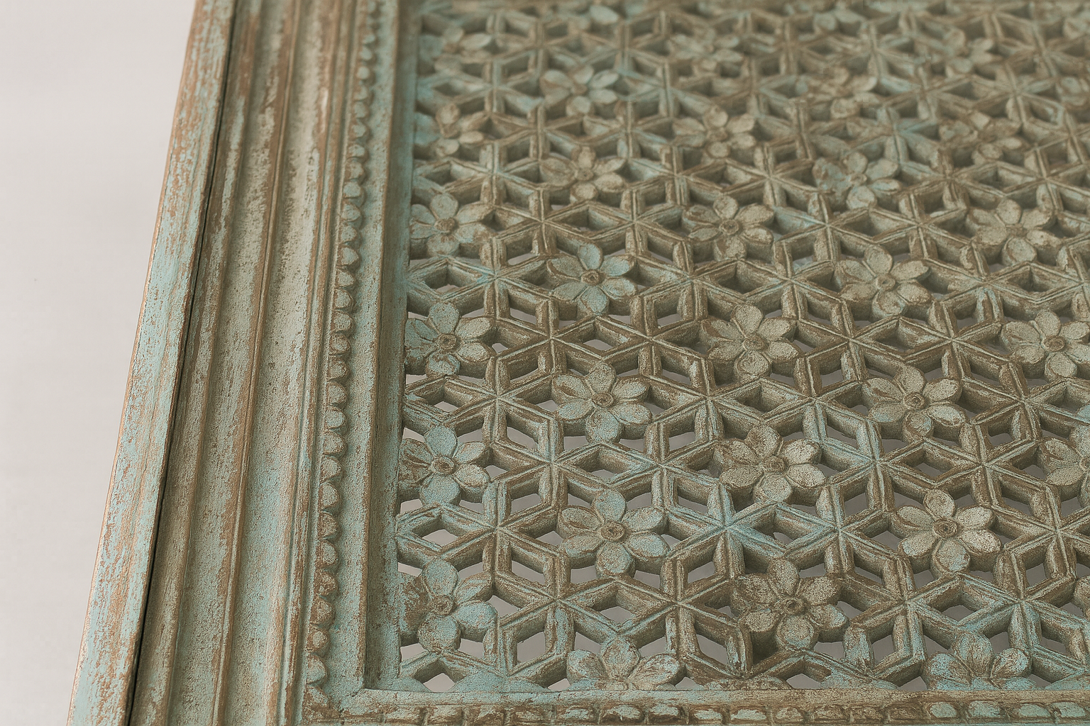 Close up image of a hand carved mango wood coffee table with floral pattern and multi-layer finish; vintage-inspired coffee table, 120 × 90 × 45 cm.