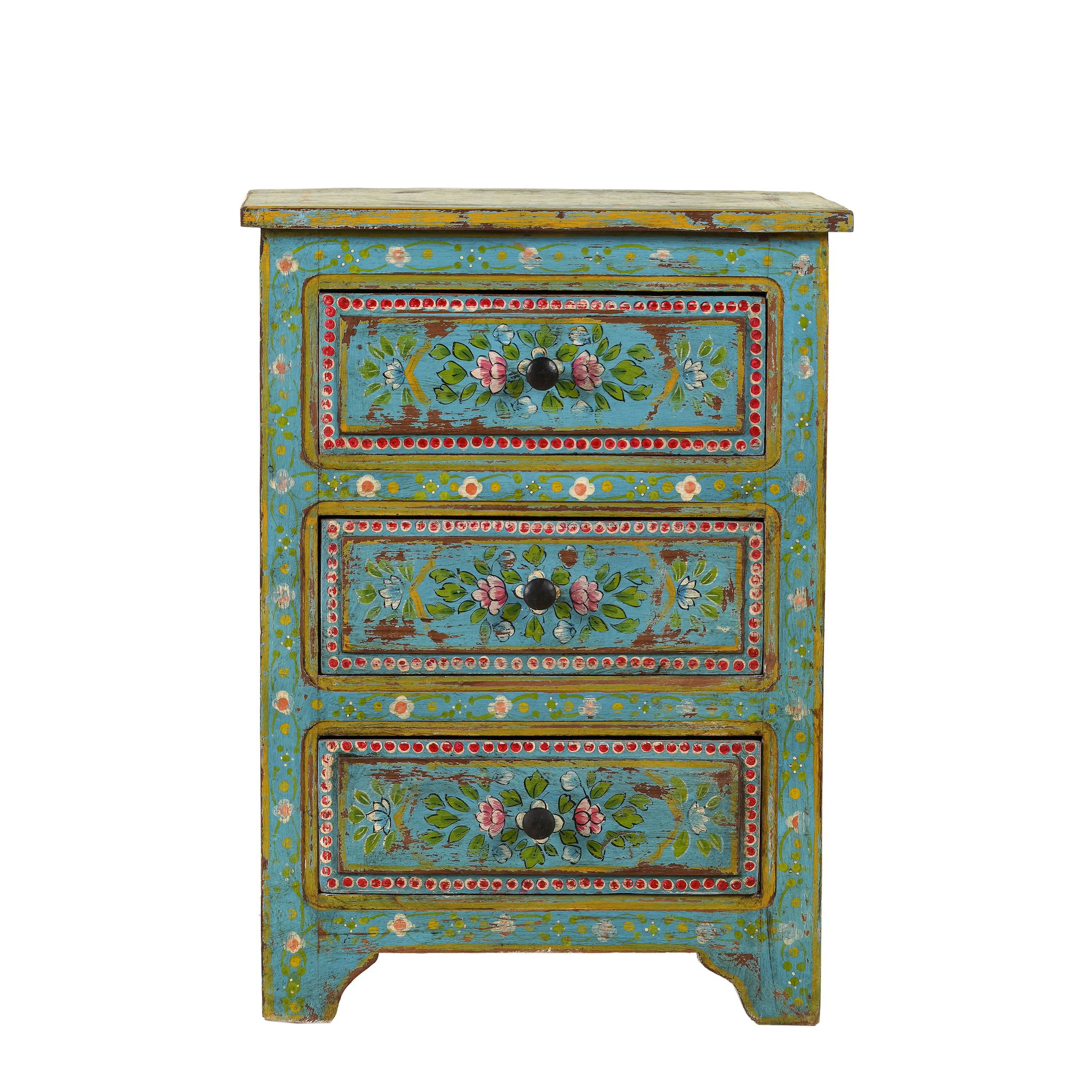 White background image of a  hand-painted reclaimed wood nightstand with vibrant colours and floral patterns, featuring three drawers, placed next to a vase with dried plants.