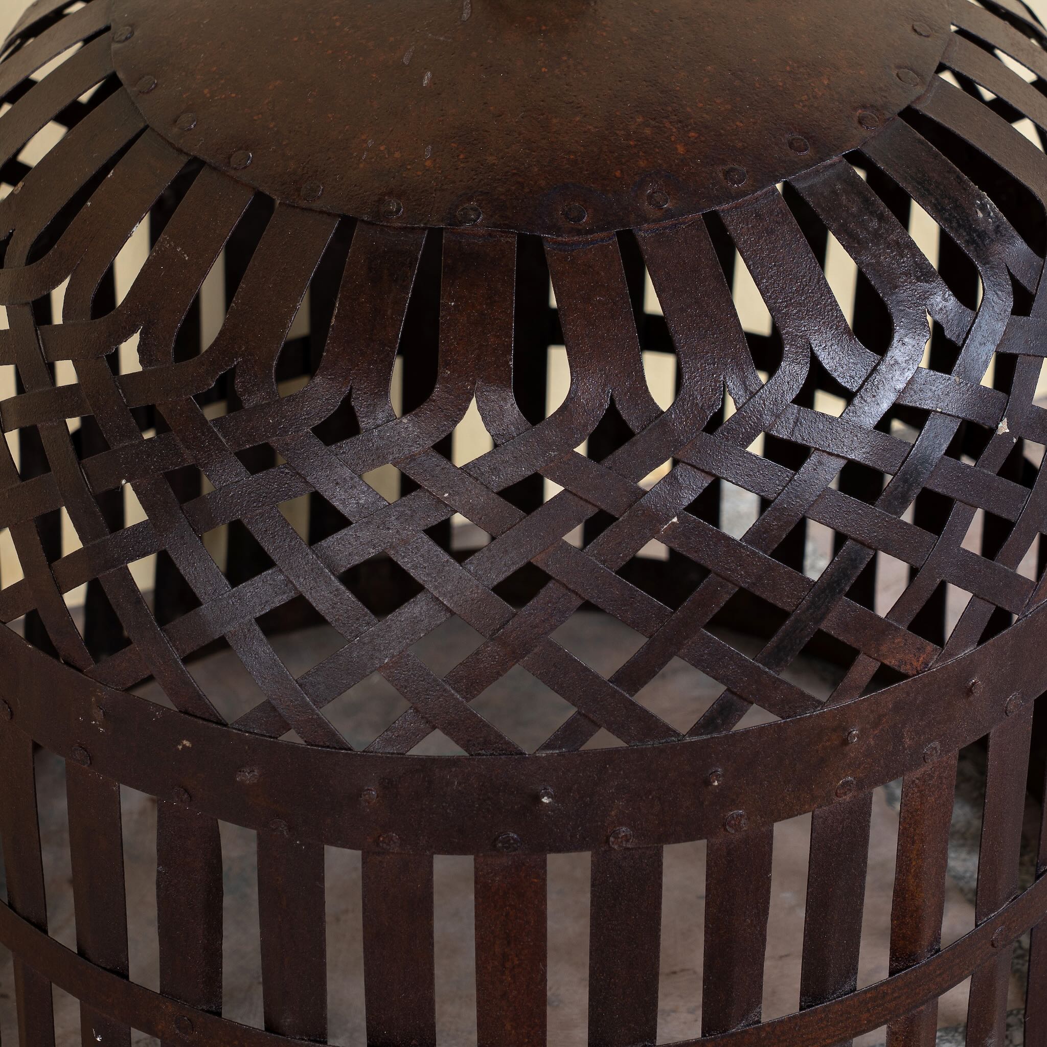 Close up image of a Chahna rusted-style metal pendant light with hand-forged lattice and slatted design, suspended by an iron chain—an artisan piece from our collection of hand crafted metal lamps and compact metal pendant lights.