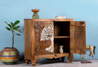 Open door image of a mango wood cupboard with hand carvings in tree of life design.