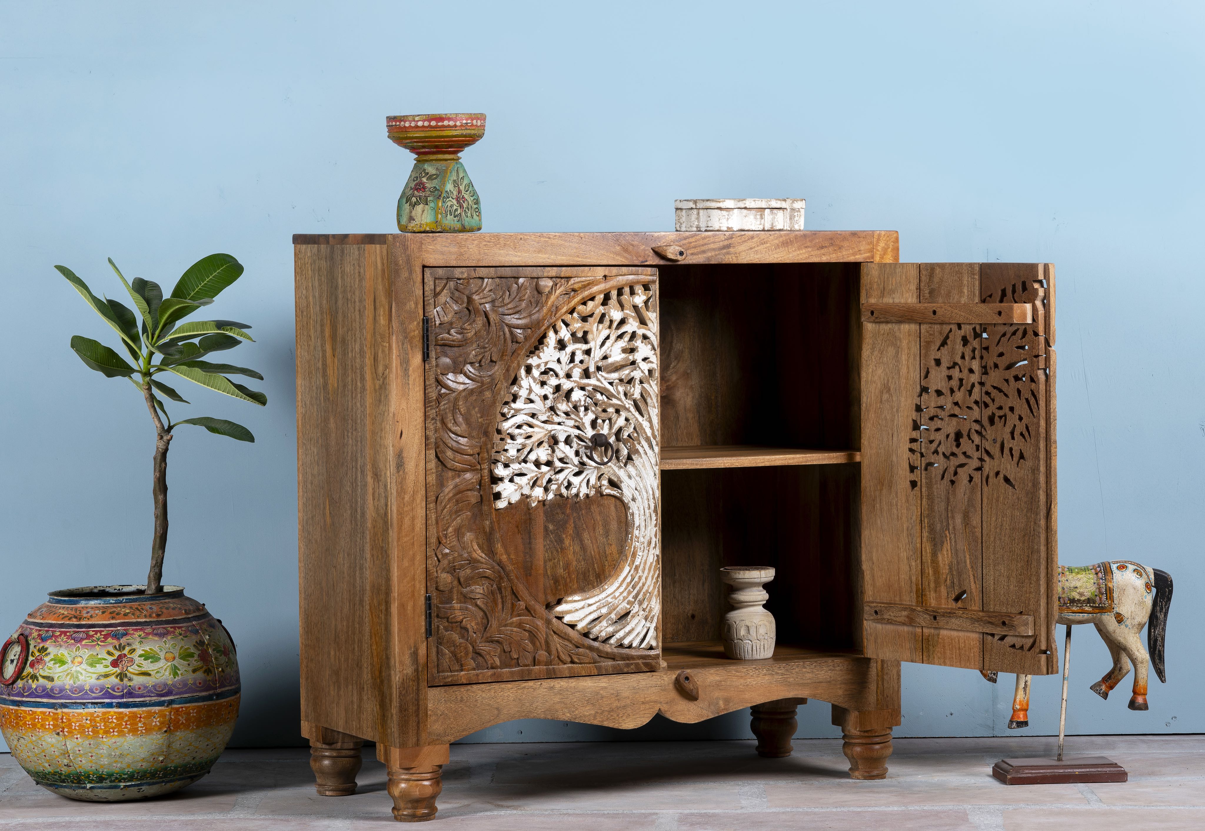 Open door image of a mango wood cupboard with hand carvings in tree of life design.
