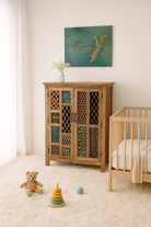 Lifestyle imagination of a artisanal mango wood cabinet with hand-carved floral and geometric lattice doors, distressed finish; ideal for boho style interiors, 100 × 45 × 130 cm.