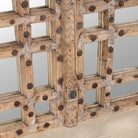 Close up of a statement wall mirror made from an old teak window frame with large square grid pattern, metal studs, and decorative center carving-  a bold blend of rustic charm and historic craftsmanship.