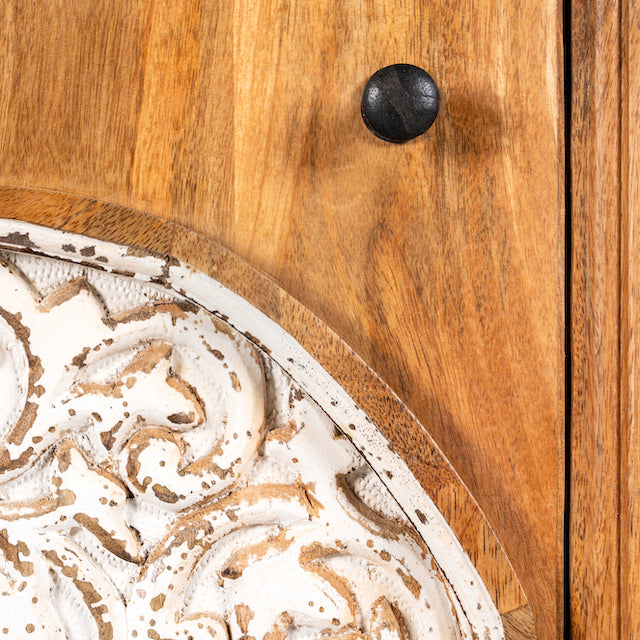 Close up image of a whitewashed mango wood nightstand with hand-carved floral door – a handcrafted example of carved wooden furniture ideal for rustic and vintage bedrooms.