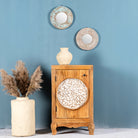 Whitewashed mango wood nightstand with hand-carved floral door – a handcrafted example of carved wooden furniture ideal for rustic and vintage bedrooms.