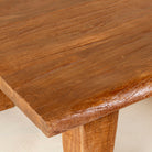 Close up picture of a rectangular rustic coffee table made from reclaimed wood, featuring a thick solid top and tapered legs with a natural, hand-finished look.