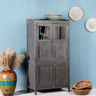 Side angle image of a shabby chic teak wood cabinet with glass doors and natural reclaimed finish – sustainable furniture ideal for vintage-style dining and living spaces.